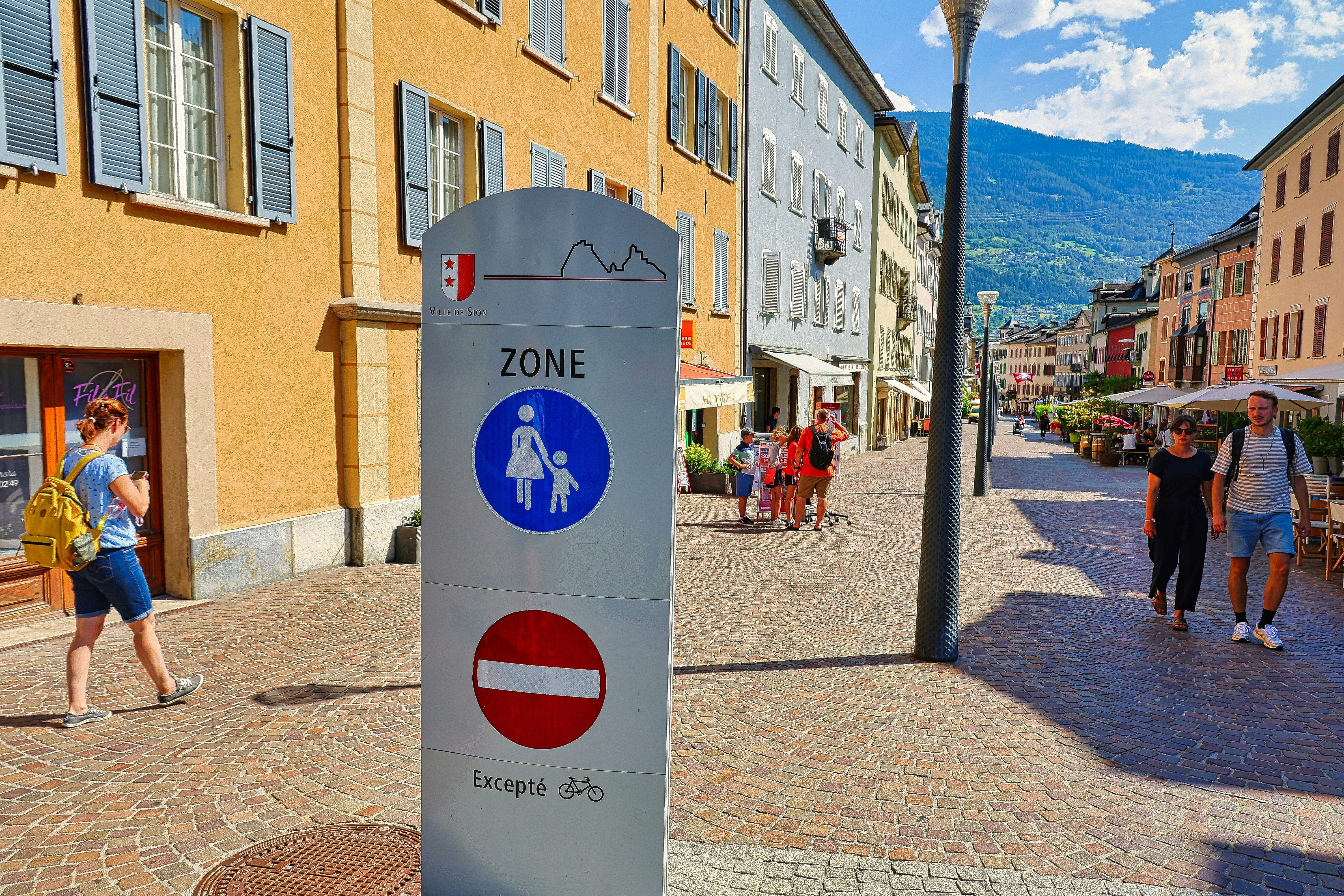 A group of people walking down a street next to tall buildings