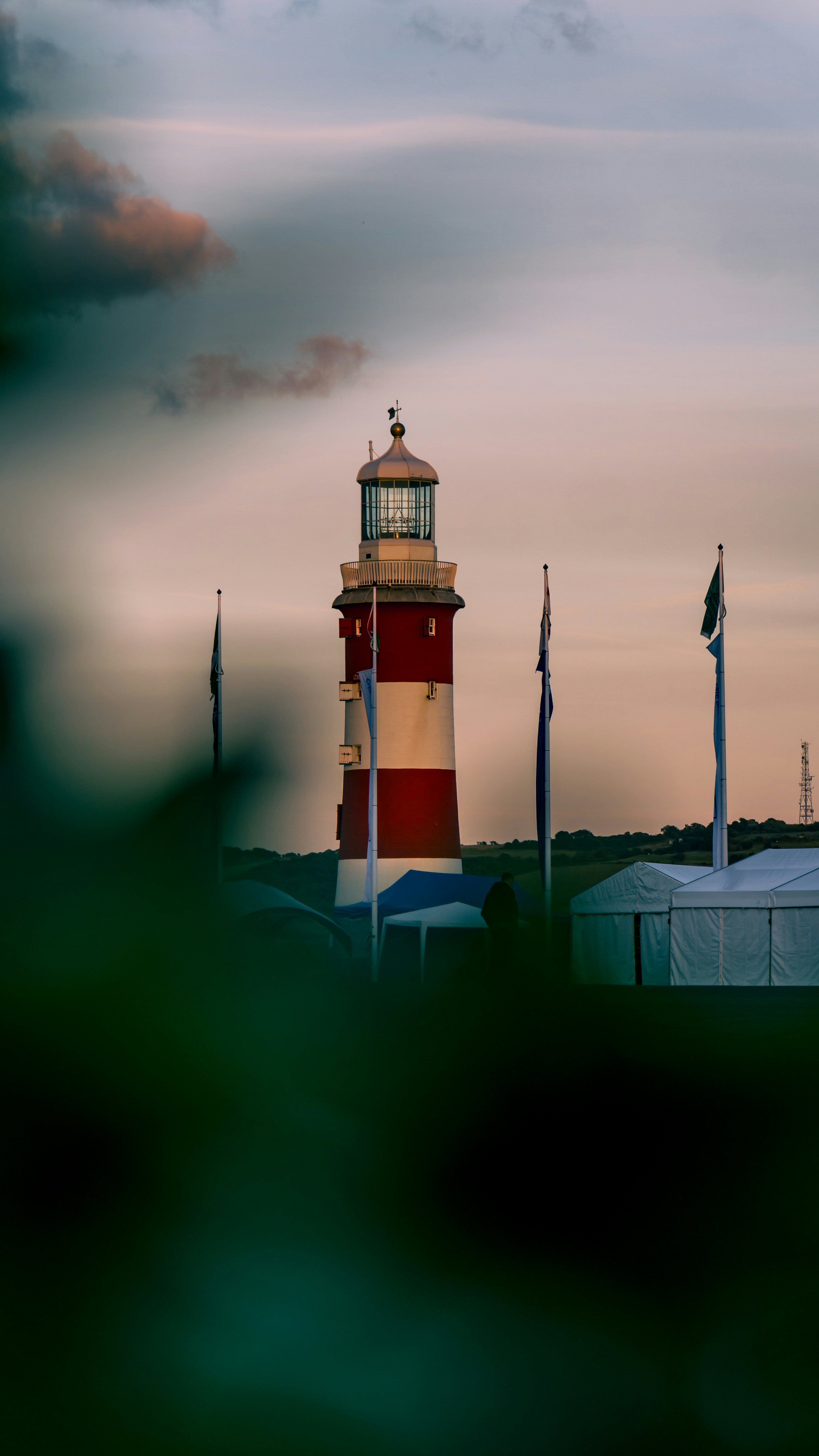 A red and white lighthouse sitting on top of a lush green field