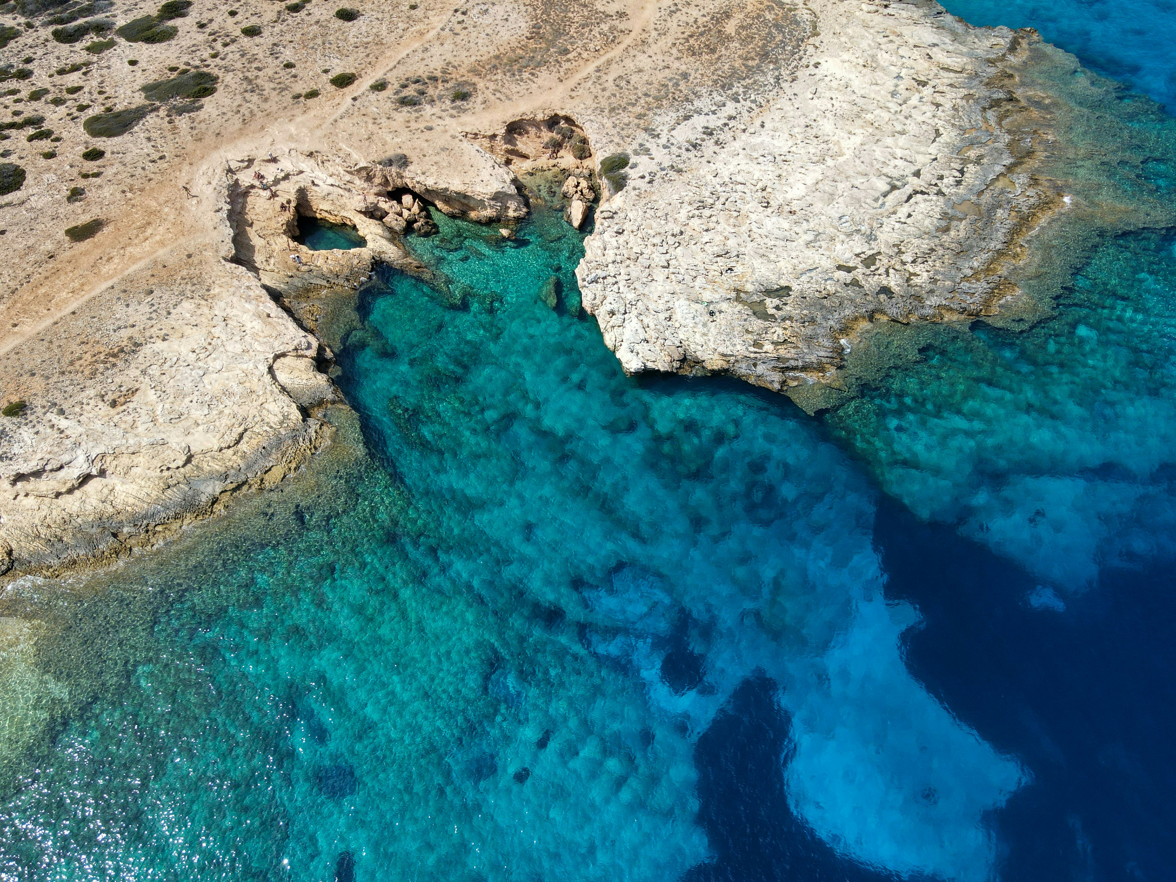 An aerial view of a rocky coastline with blue water