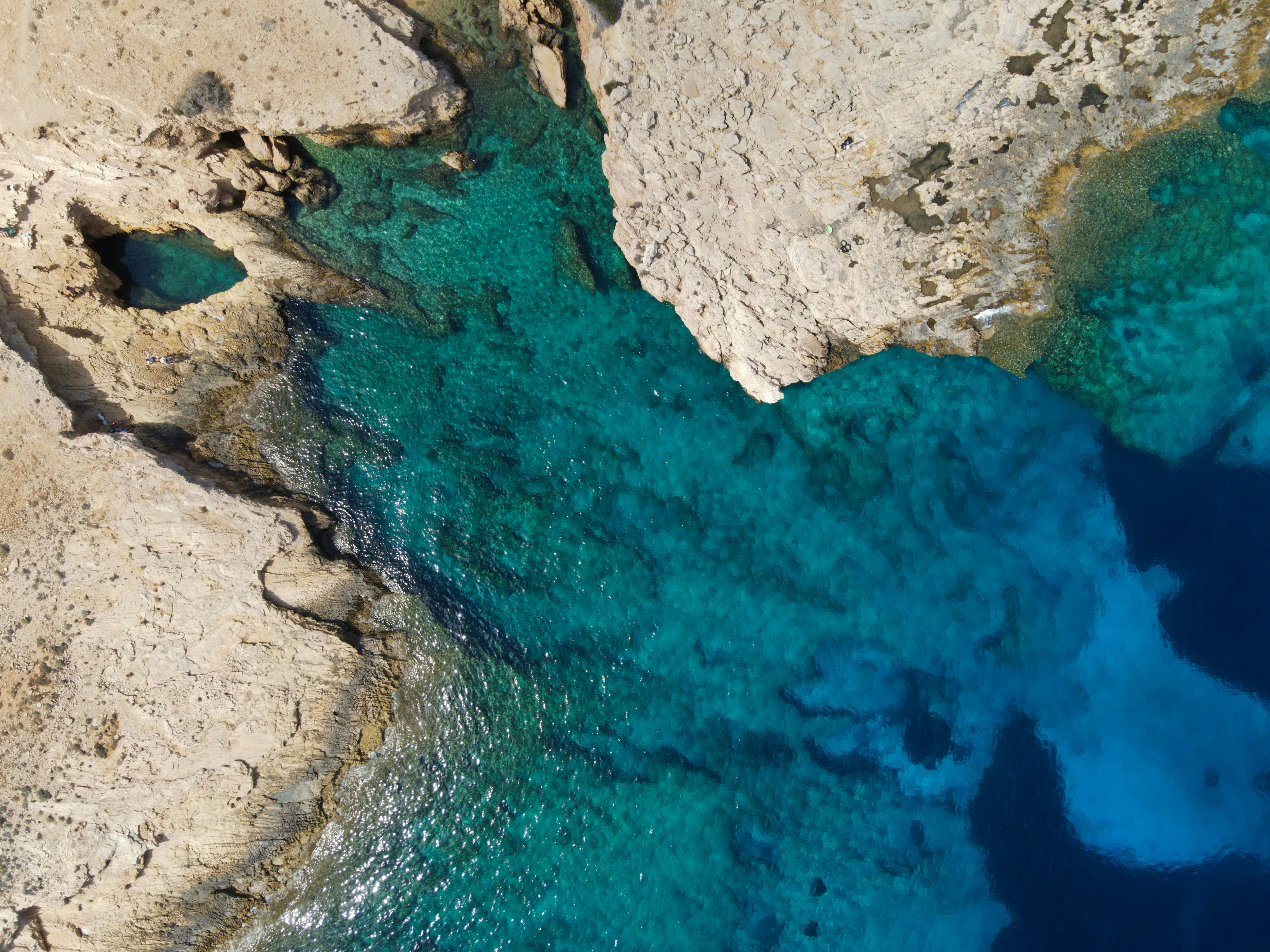 An aerial view of a rocky coastline with blue water