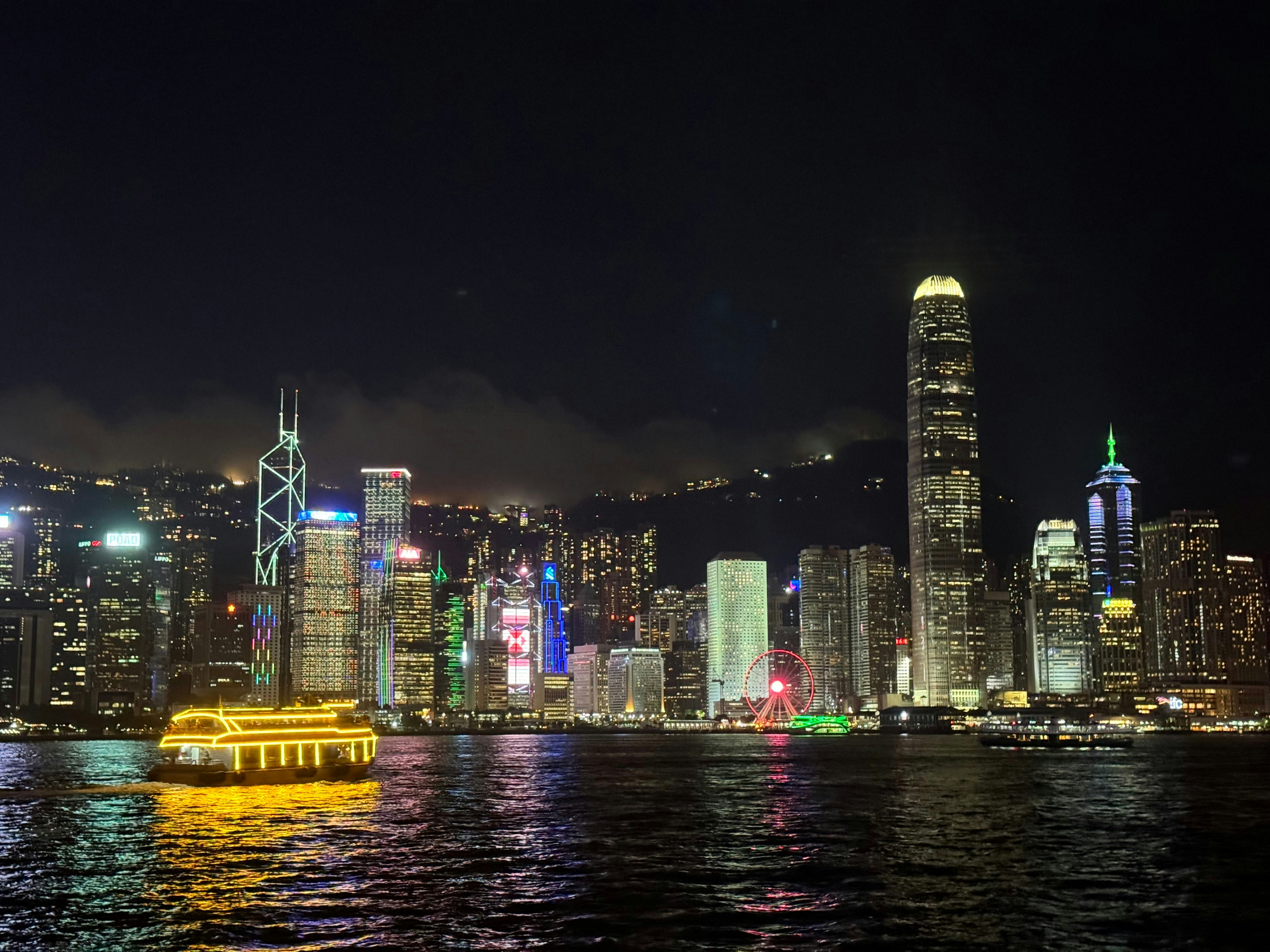 Ultra trail runners on Hong Kong mountain ridge at night with city lights below