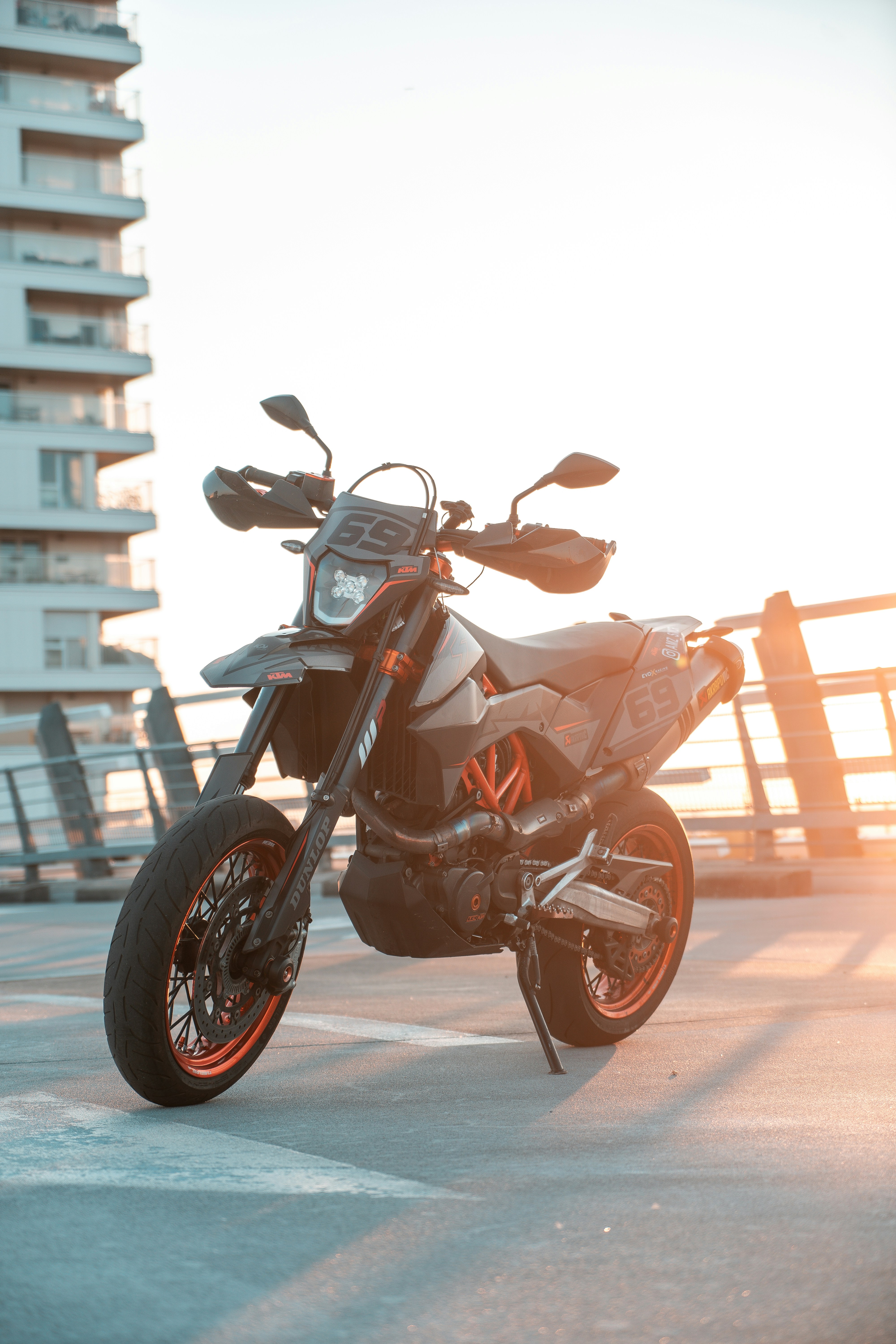 A motorcycle parked in a parking lot next to a tall building