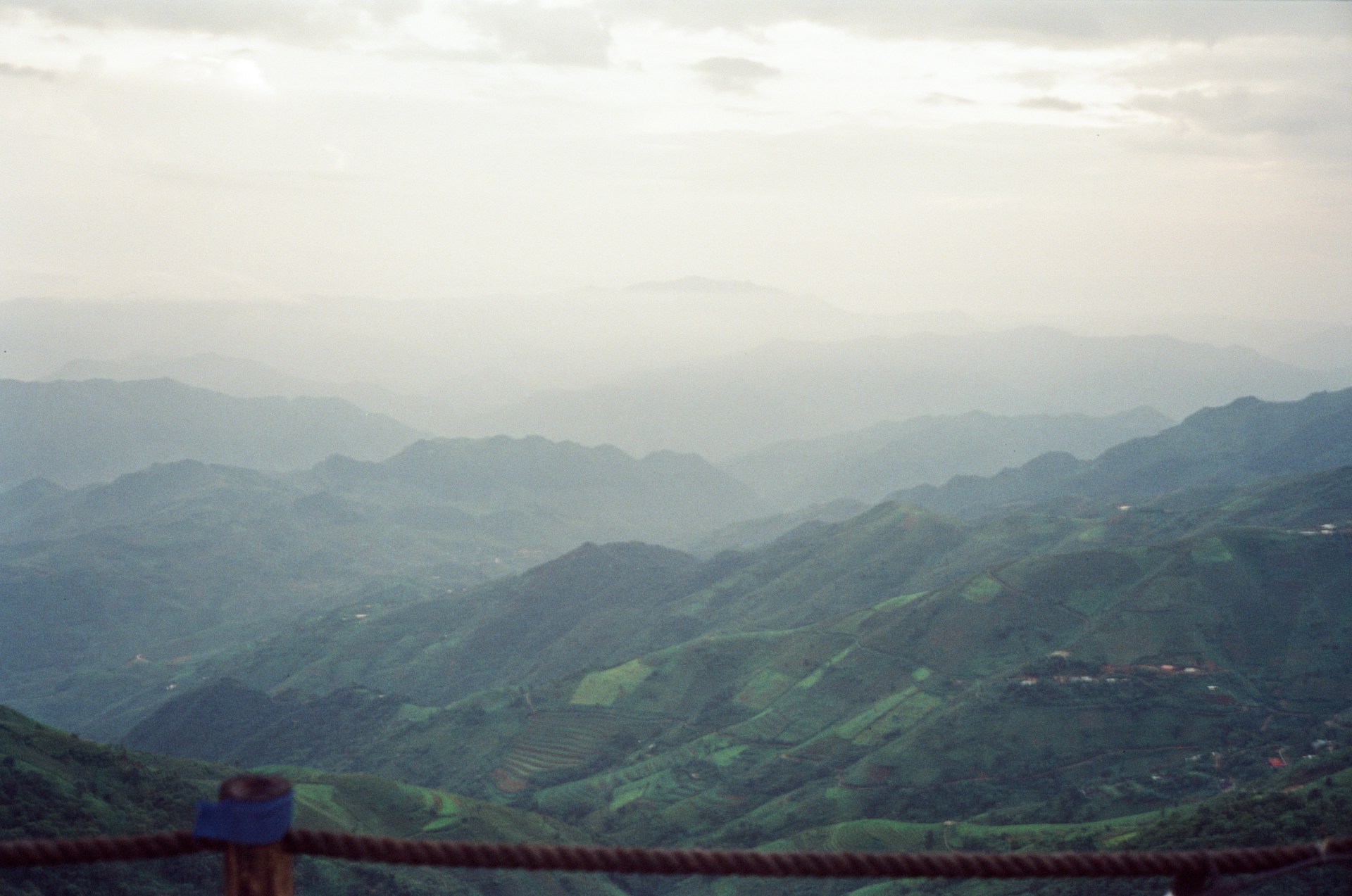 A bird perched on a fence overlooking a mountain range