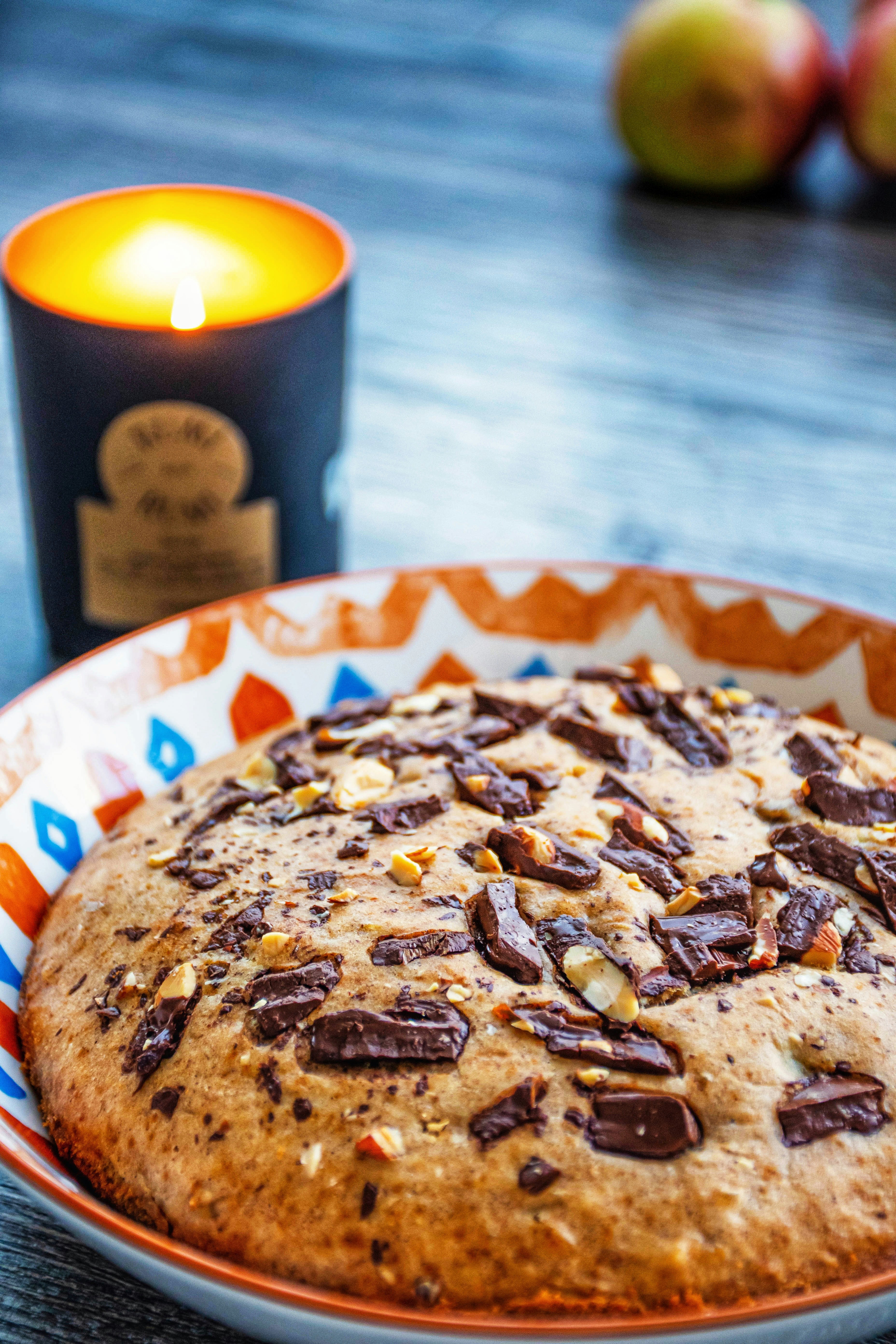 Ein Schokoladenkeks auf einem Teller neben einer Kerze