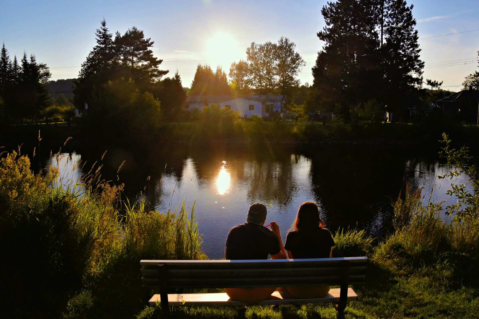 Two people sitting on a bench near a lake