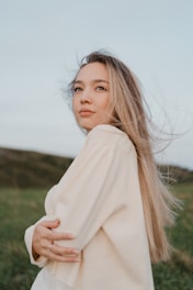 A woman standing in a field with her hair blowing in the wind