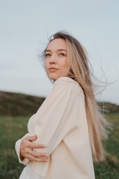 A woman standing in a field with her hair blowing in the wind