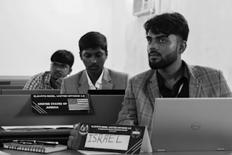 A group of men sitting at a table with laptops