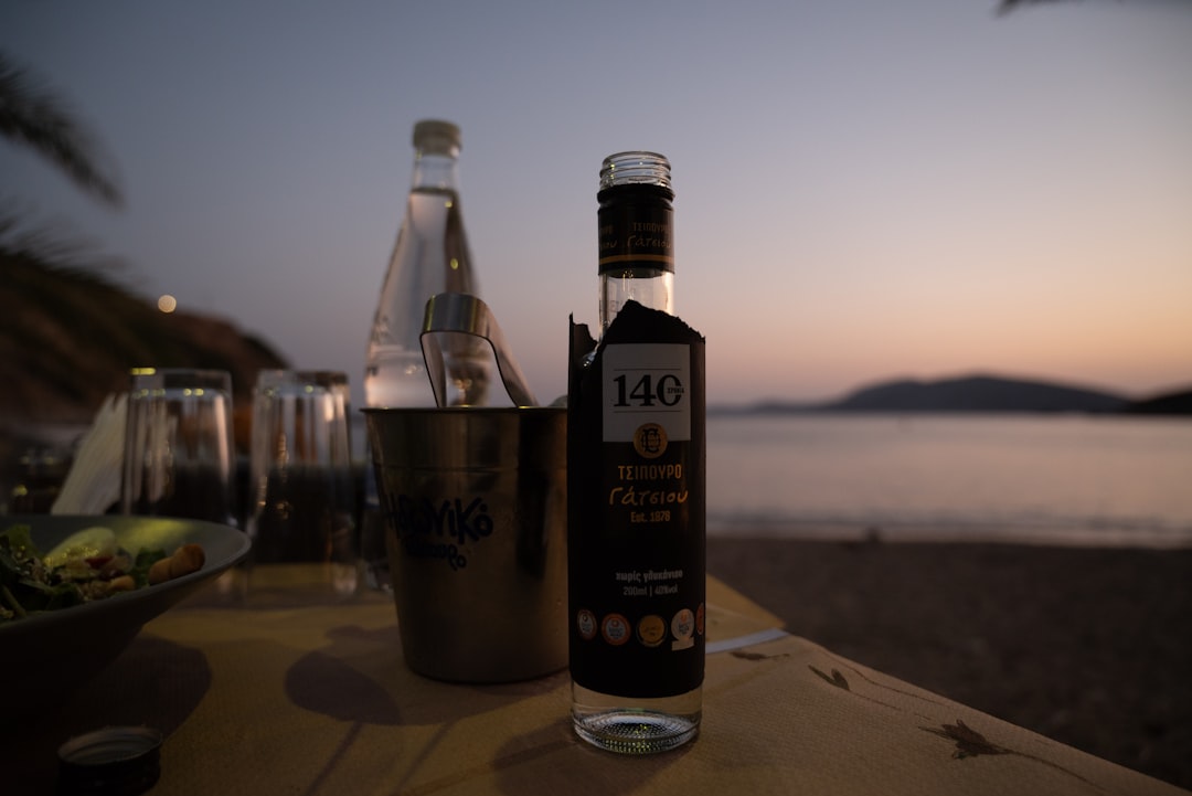 A bottle of wine sitting on top of a wooden table, Close To The Sea