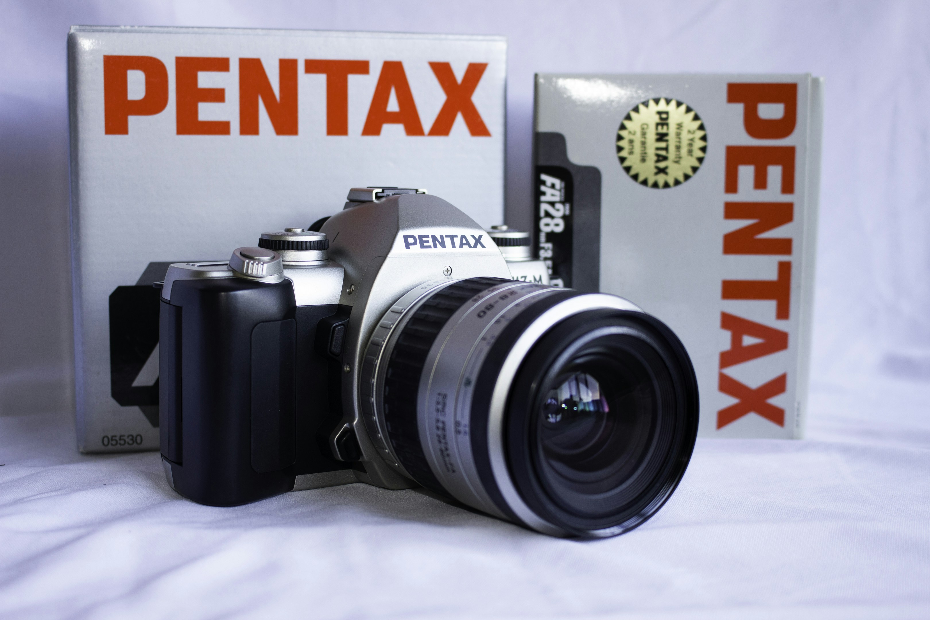 A pentax camera sitting next to a box