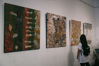 A woman is looking at paintings on the wall