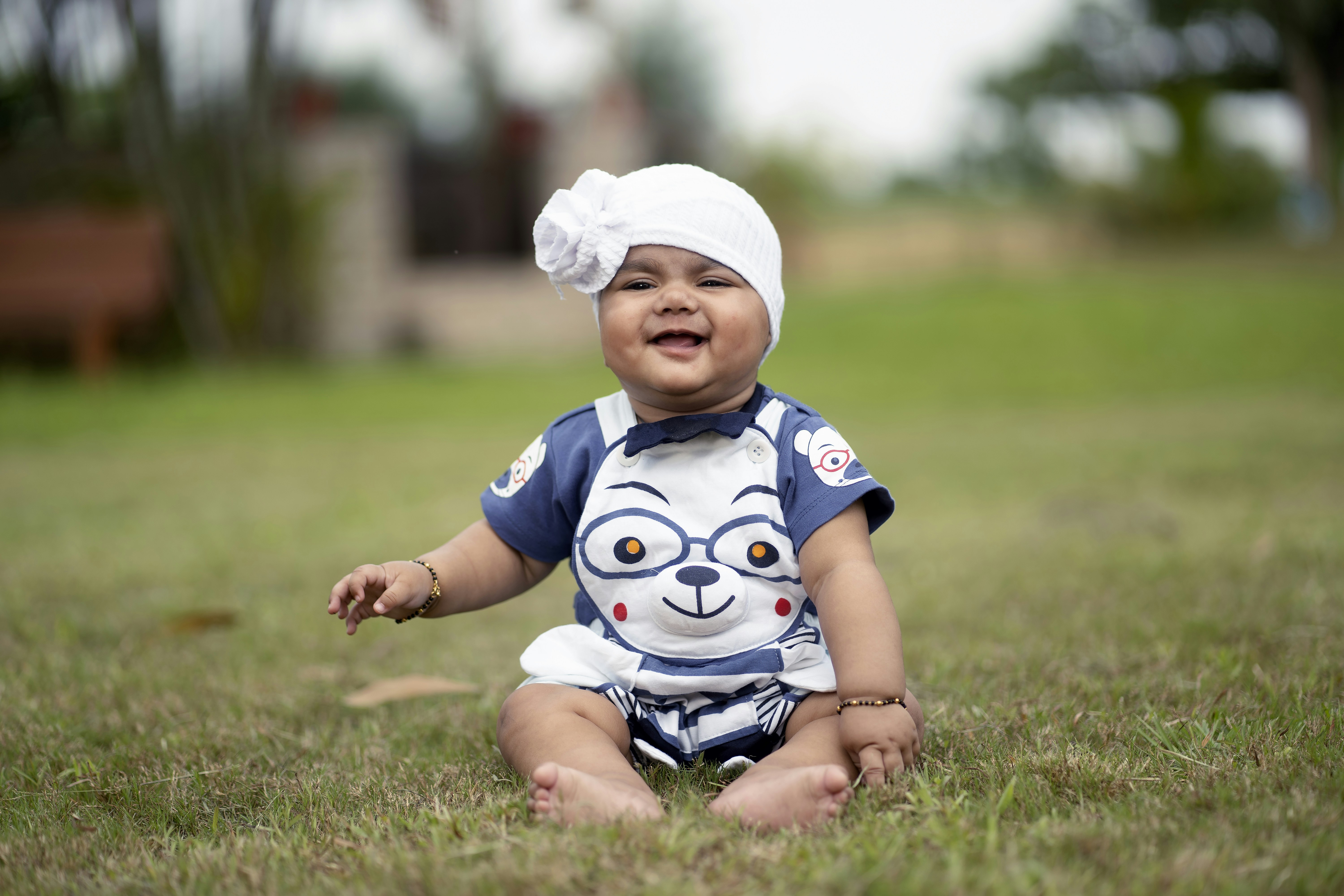 Seorang bayi duduk di rumput mengenakan sorban