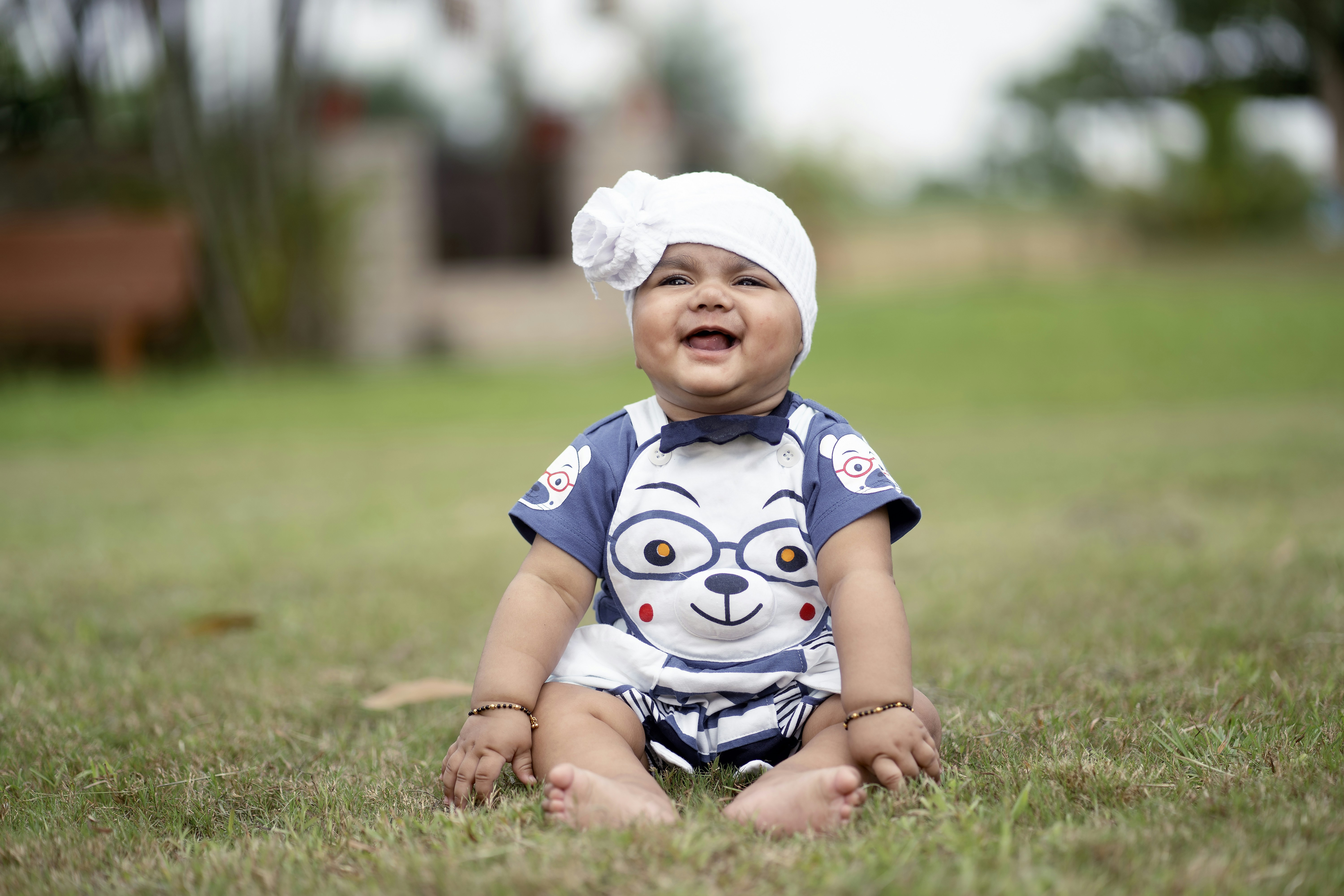 A baby sitting in the grass wearing a turban