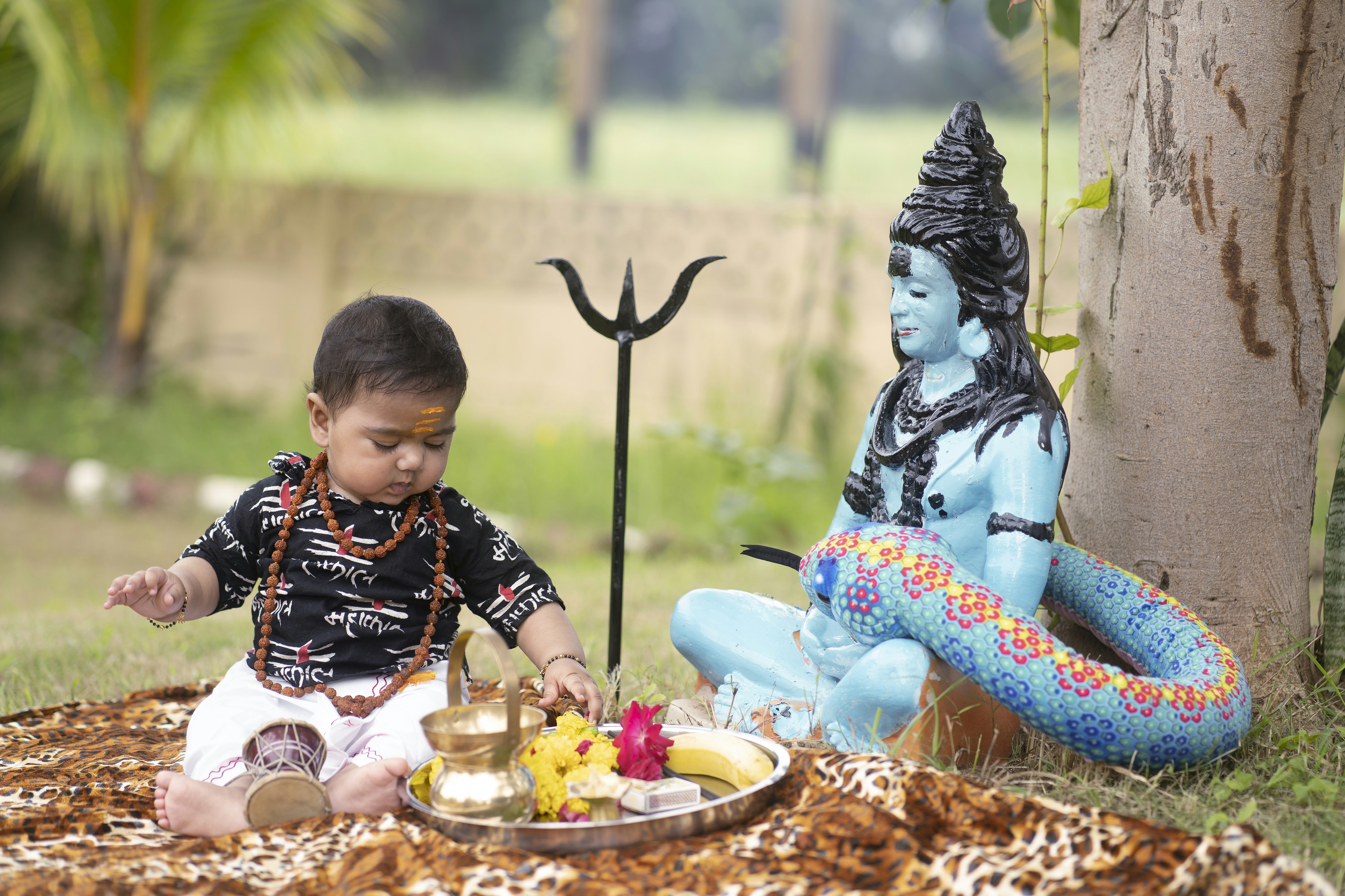 A little boy sitting on the ground next to a statue