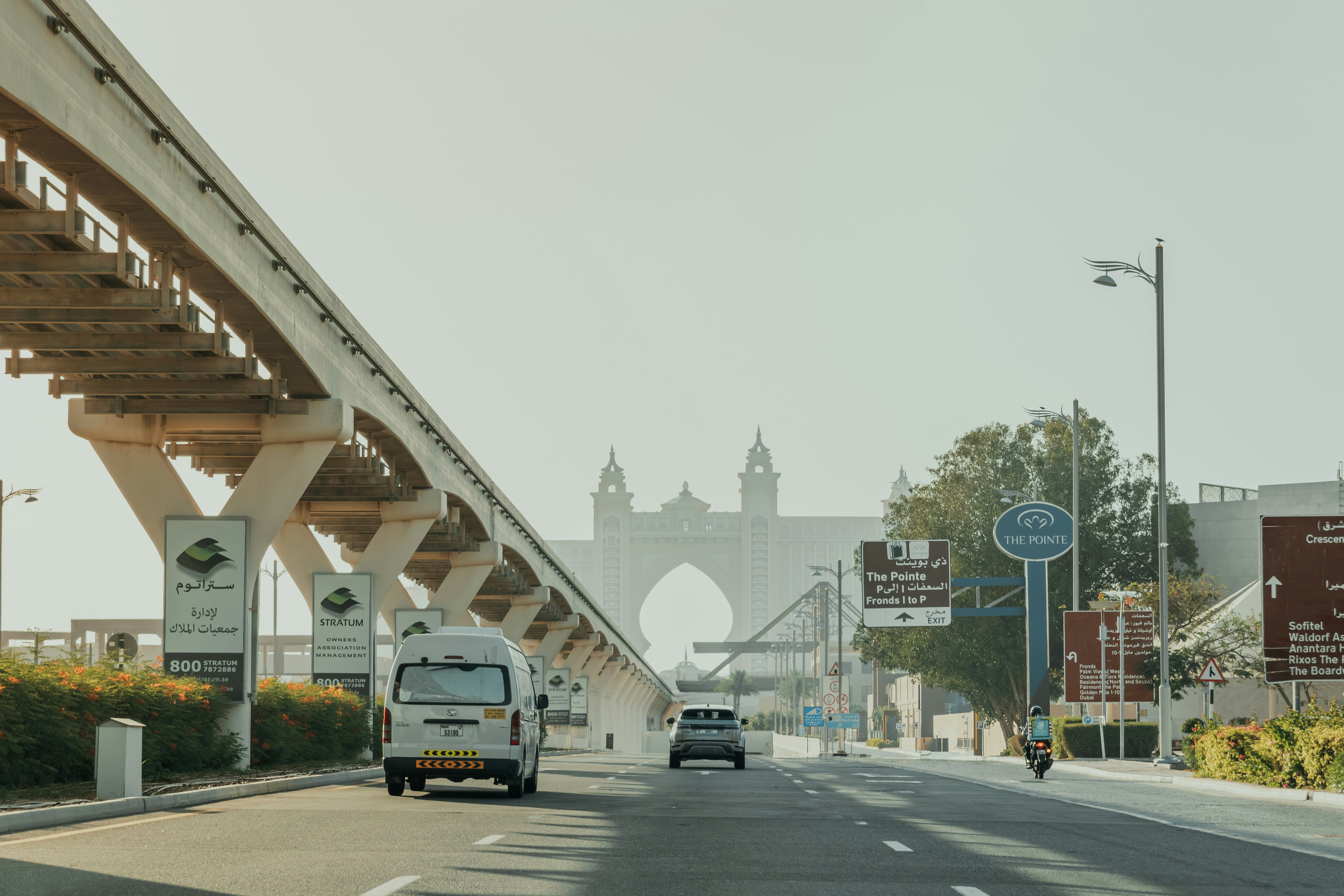 A white van driving down a street next to a bridge