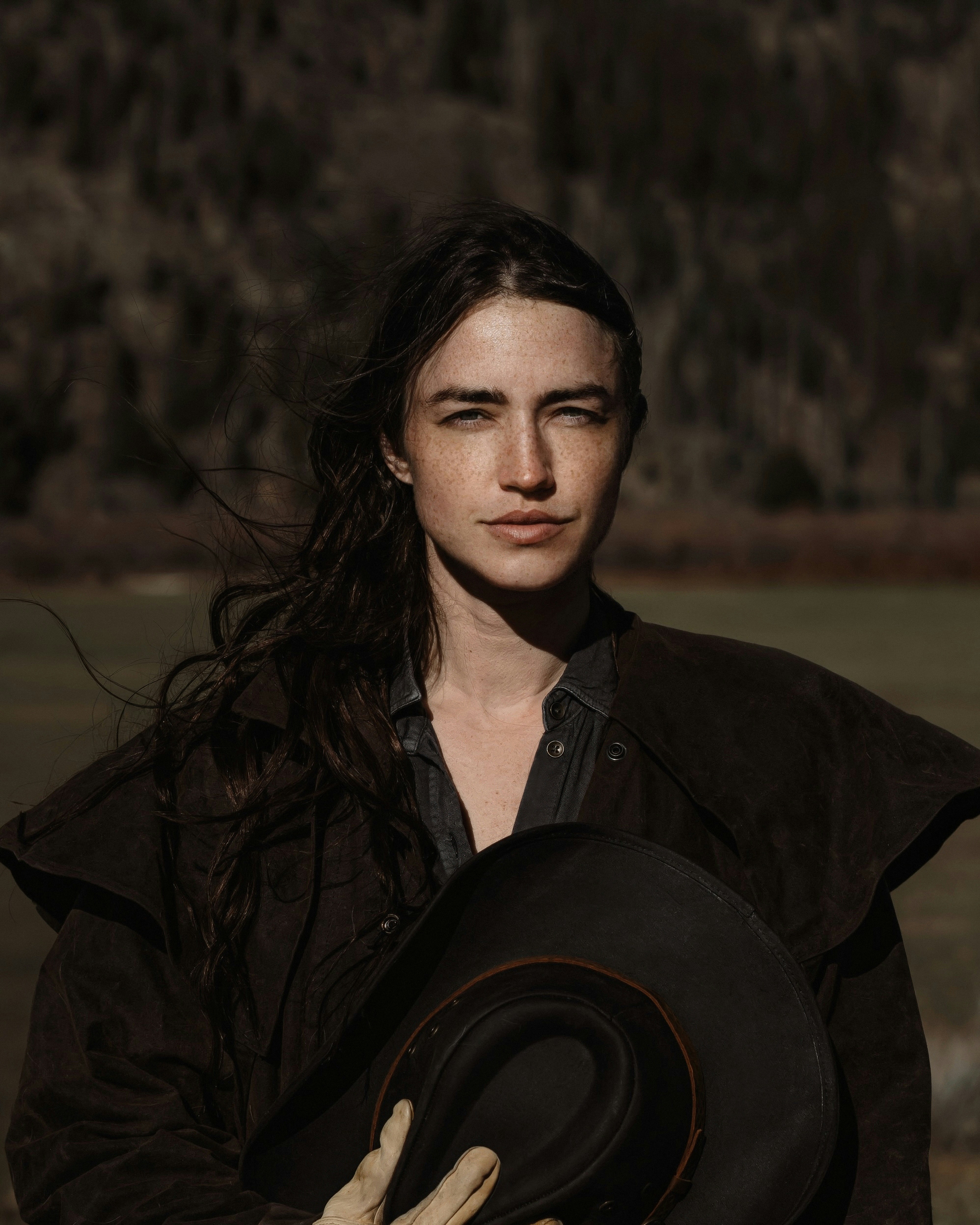 A woman holding a hat in a field