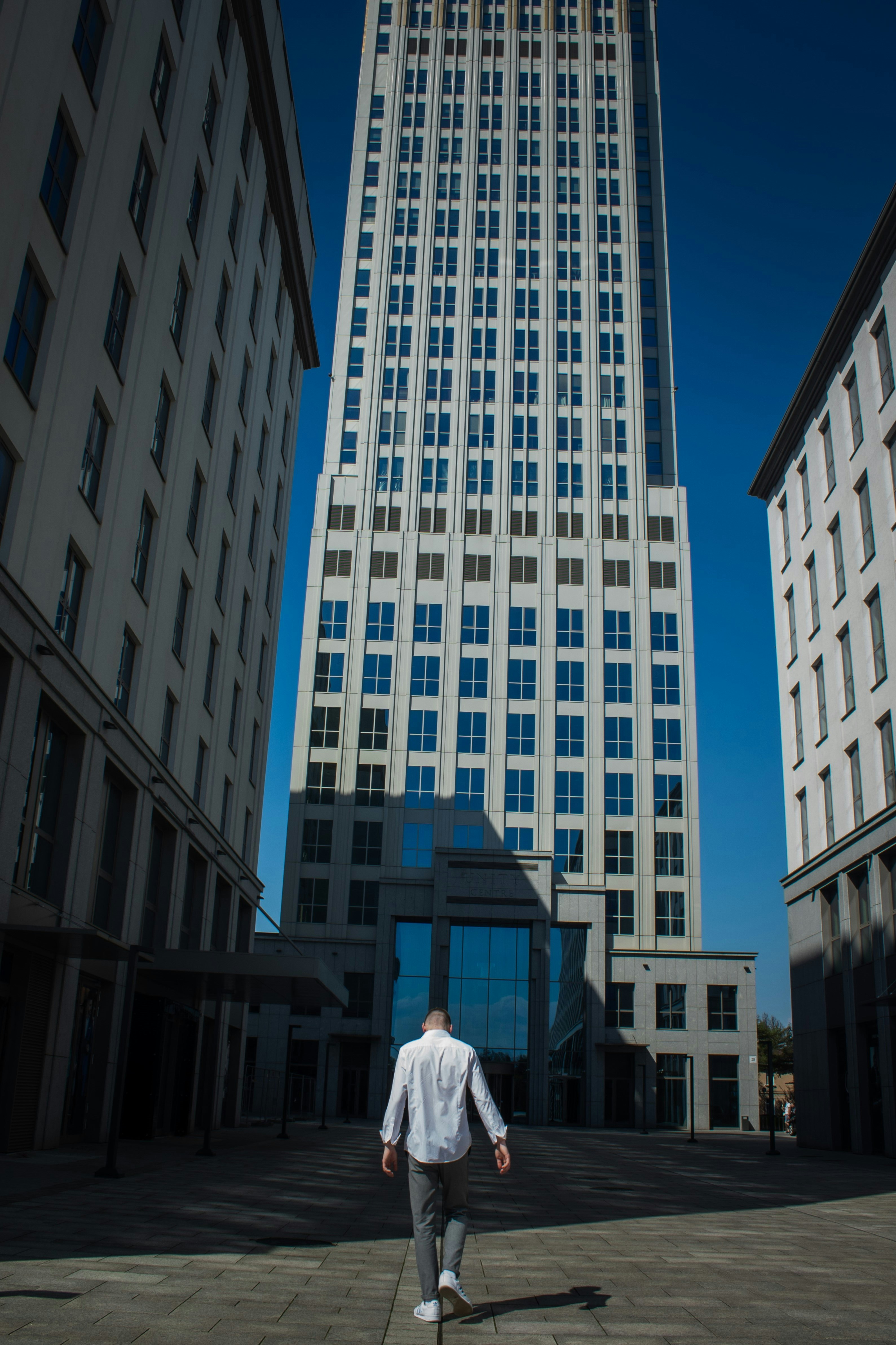 Ein Mann geht eine Straße vor hohen Gebäuden entlang