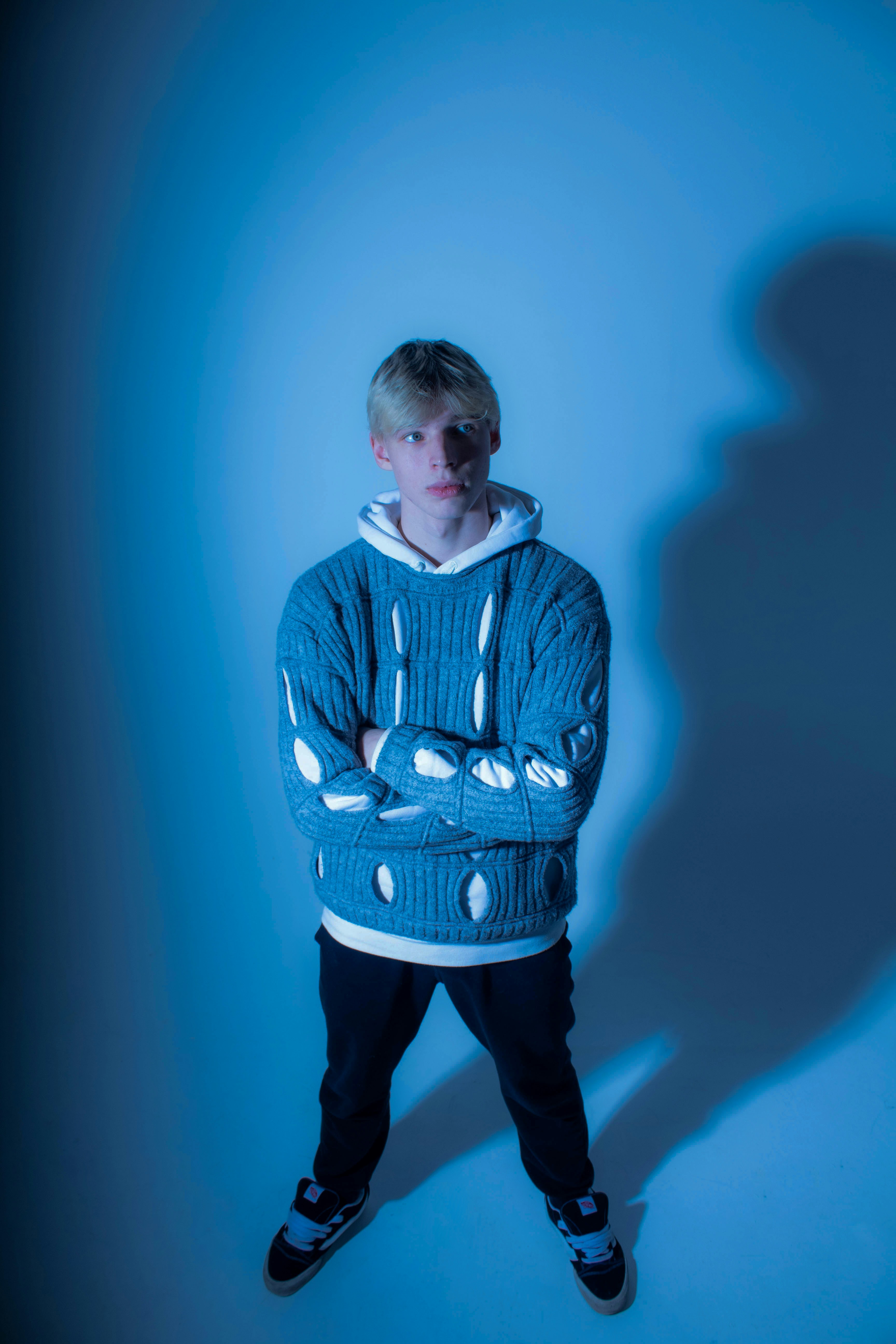 Ein junger Mann in einem blauen Pullover und einer schwarzen Hose