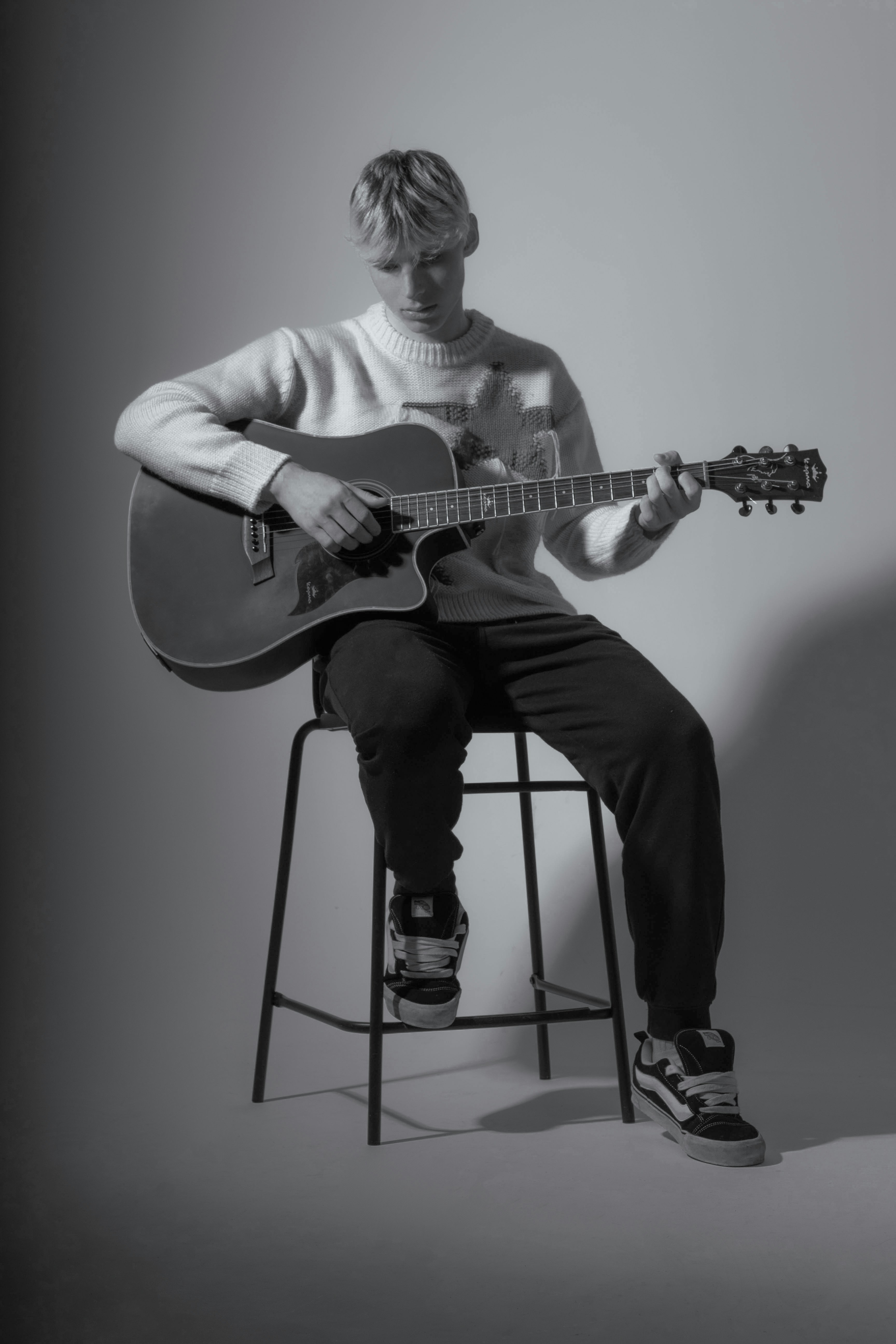 Ein Mann sitzt auf einem Hocker und spielt Gitarre