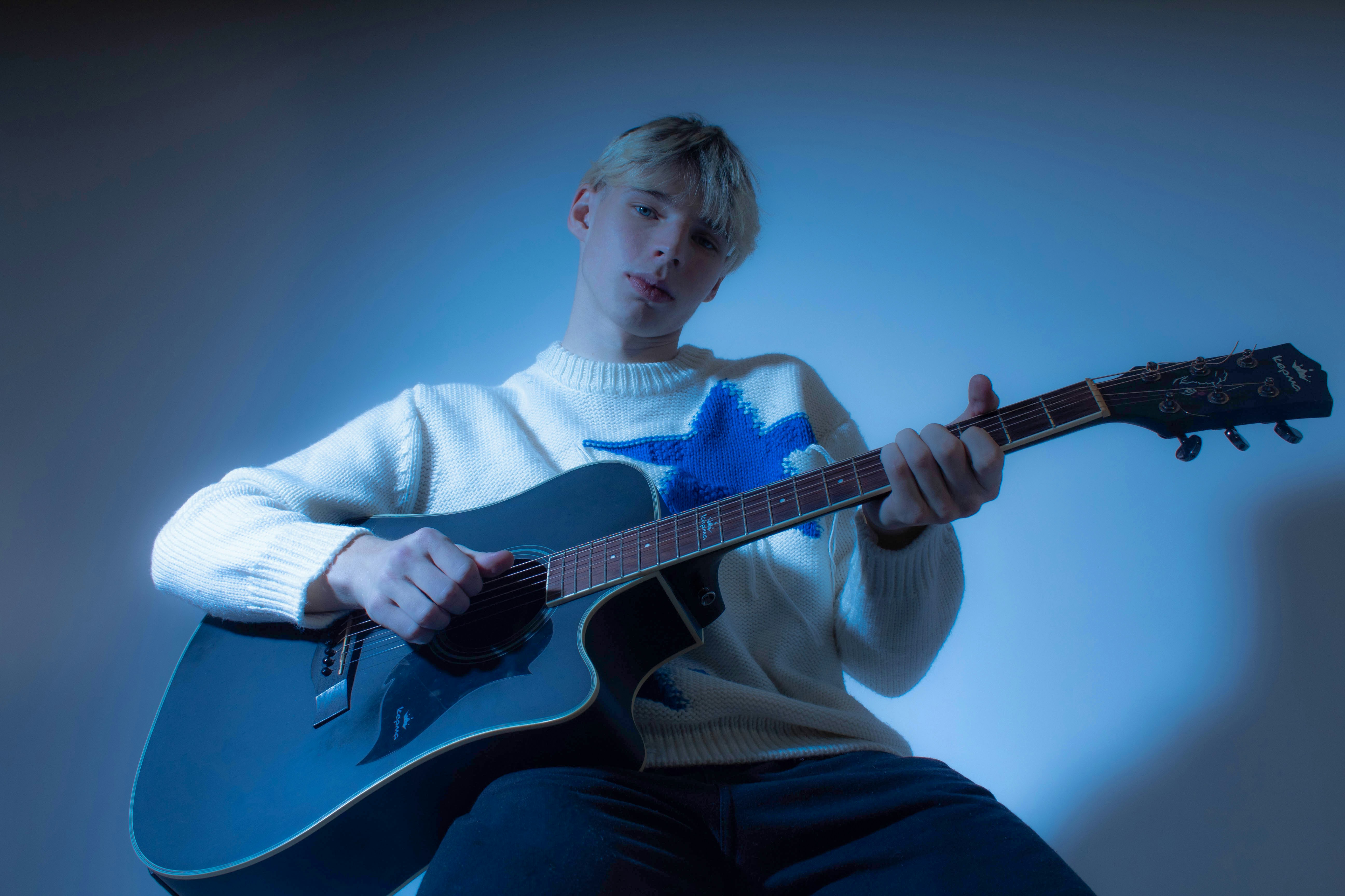 Ein Mann sitzt auf einem Stuhl und spielt Gitarre