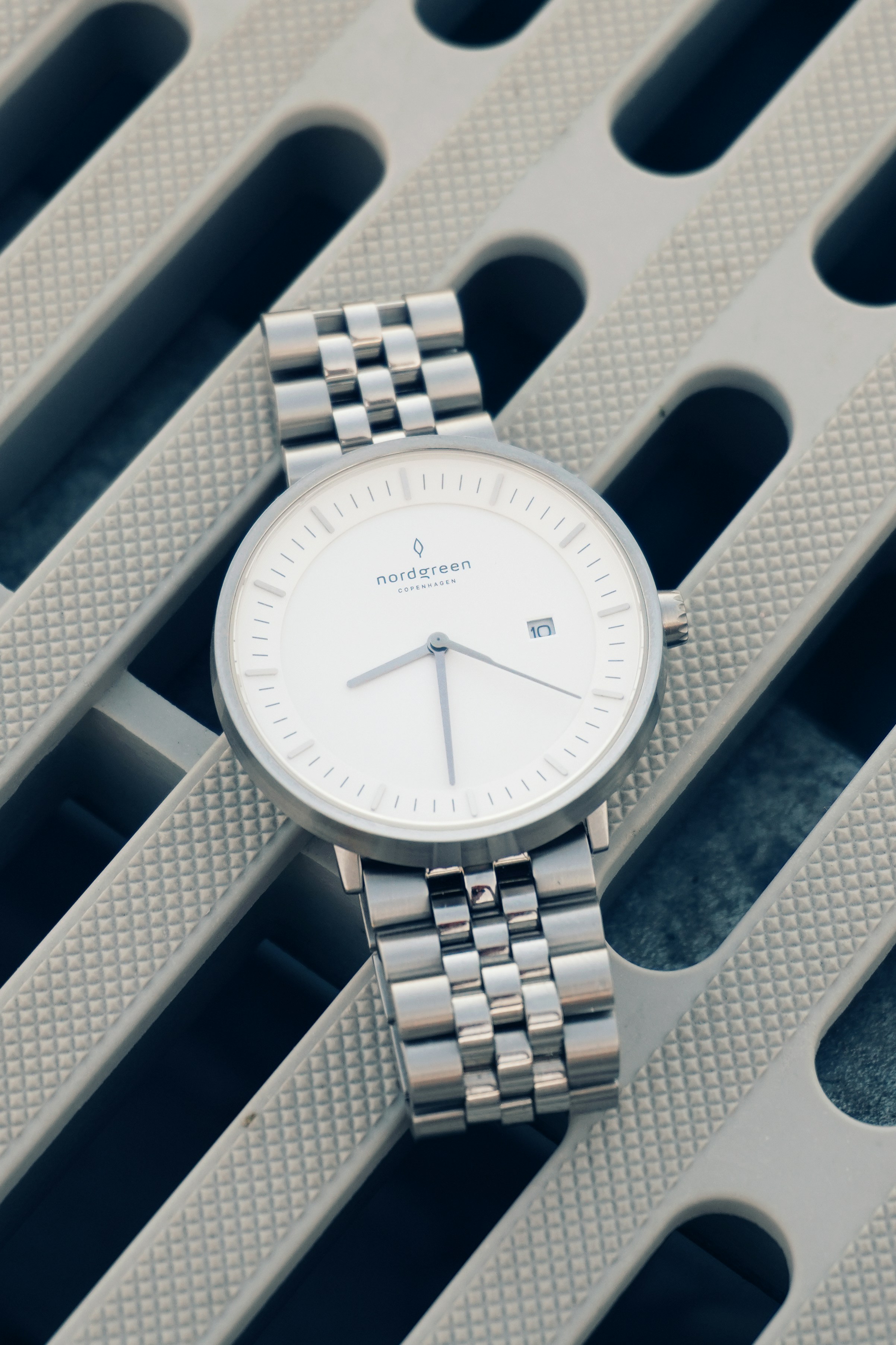 A silver watch sitting on top of a table