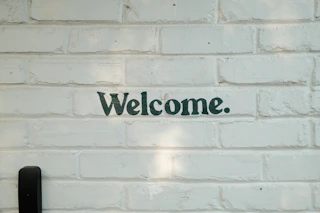 A brick wall with a welcome sign on it