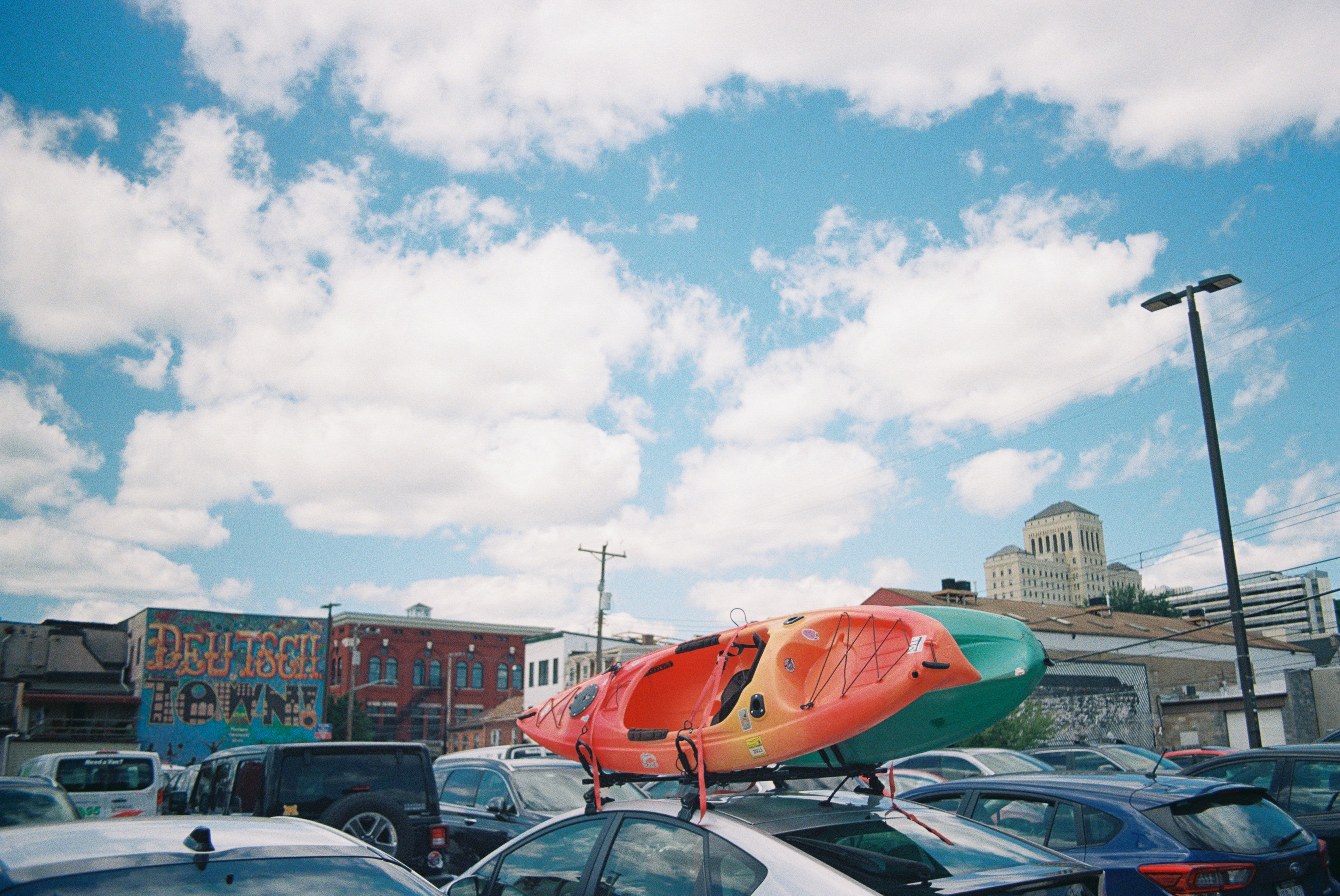 Red kayak securely mounted on car roof rack in parking lot ready for transport. Photo by Zhen Yao on Unsplash