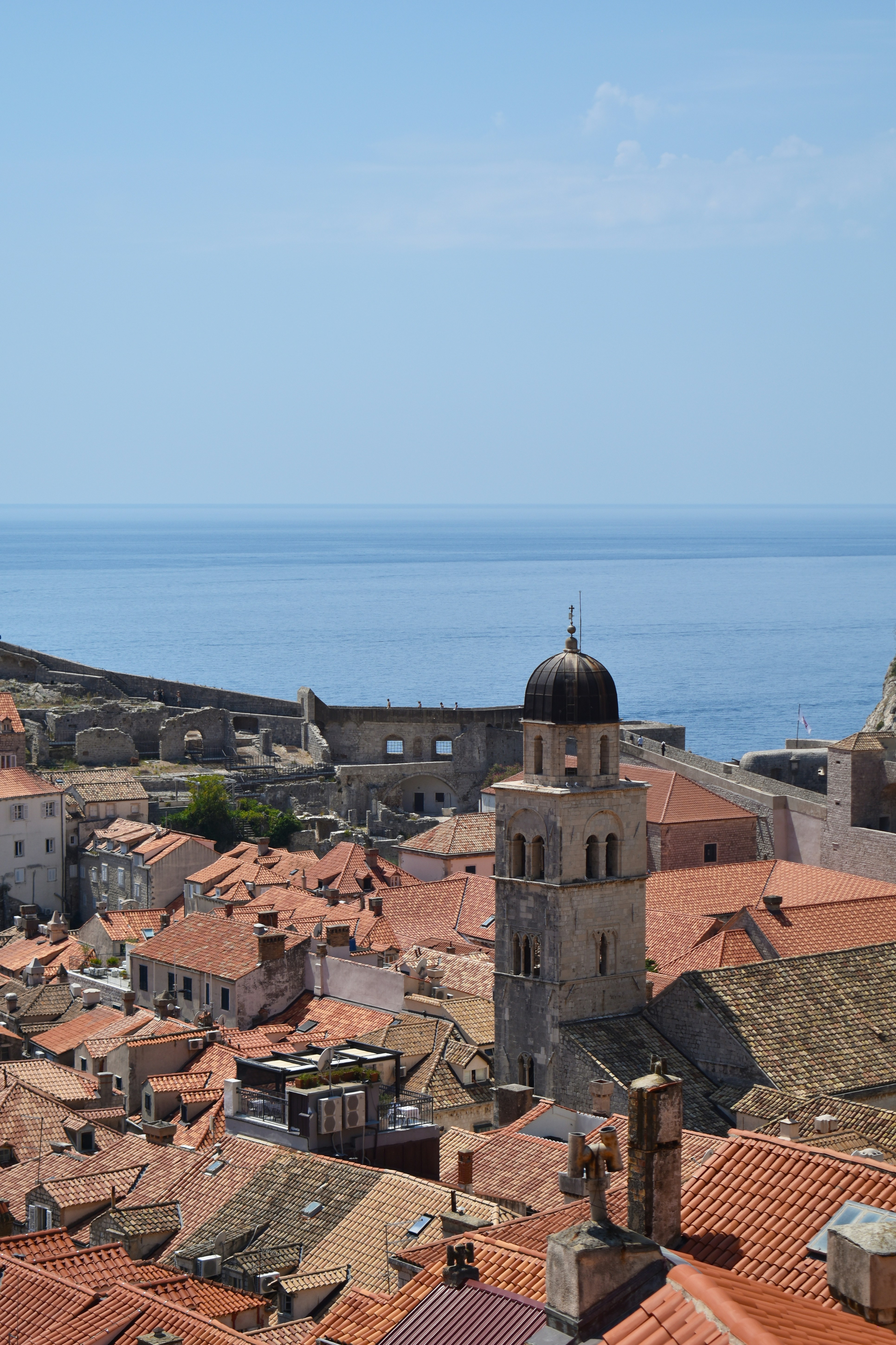 A view of a city with red roofs and a body of water in the background