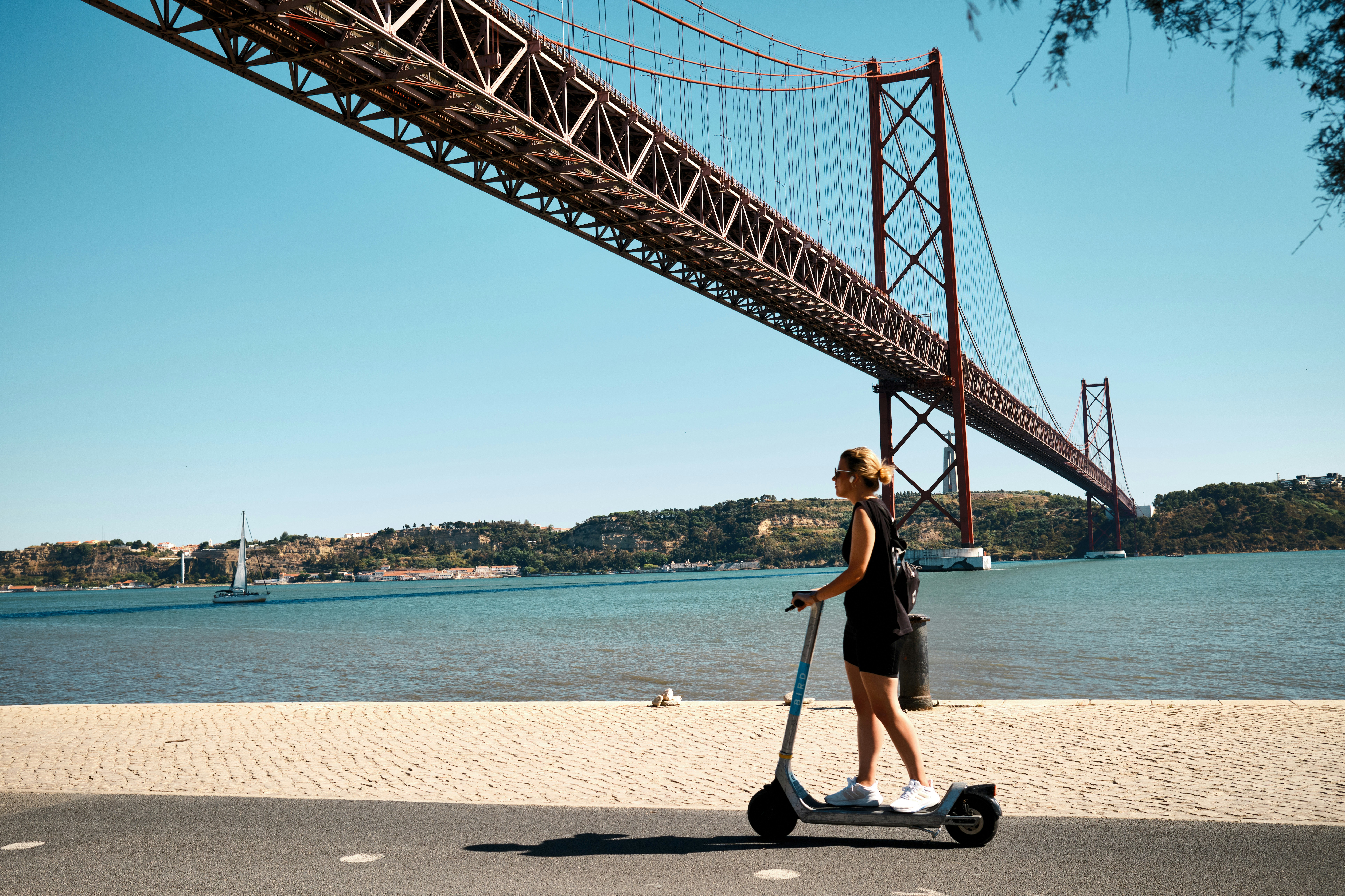 Uma mulher andando de scooter sob uma ponte