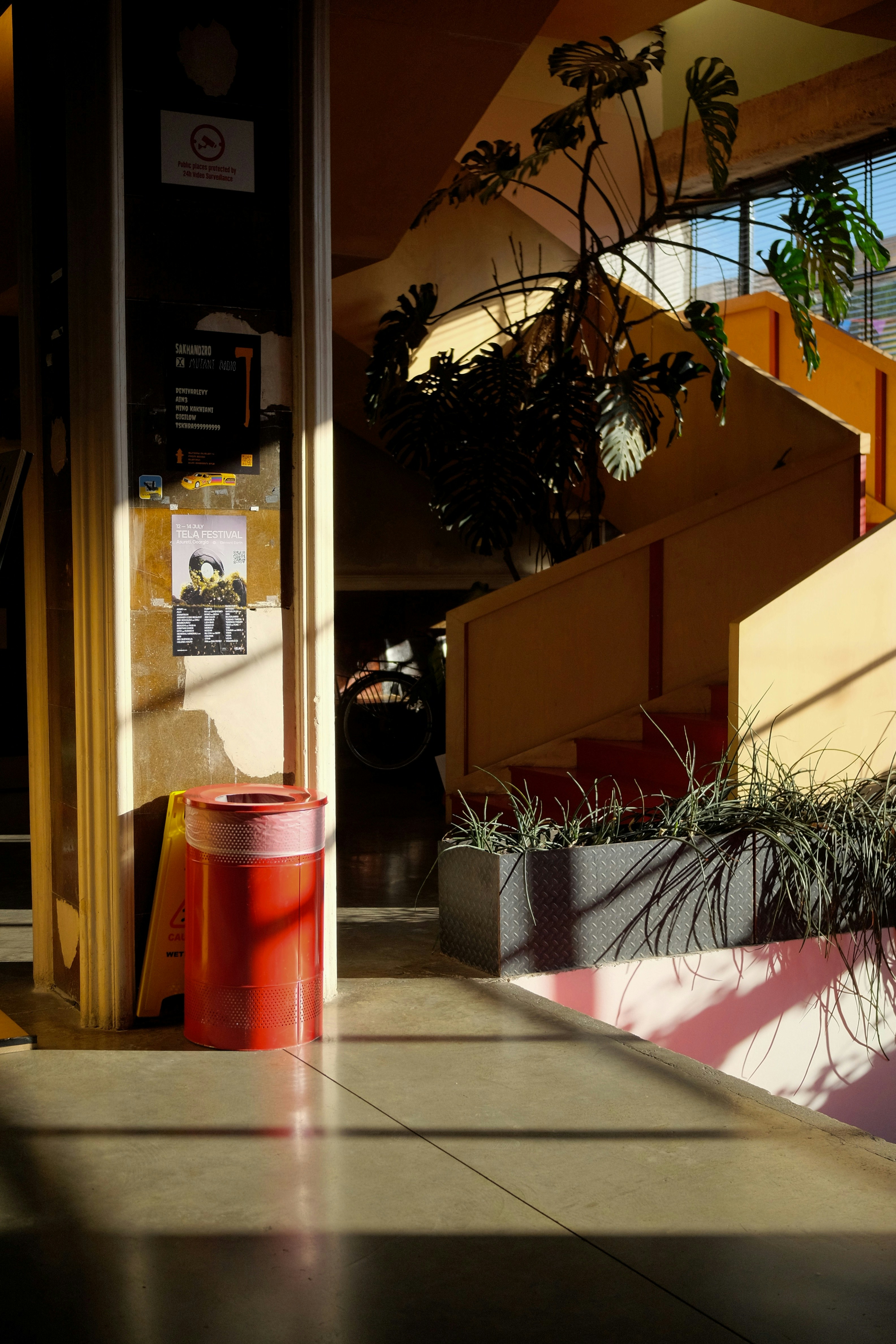 A red trash can sitting on the side of a building