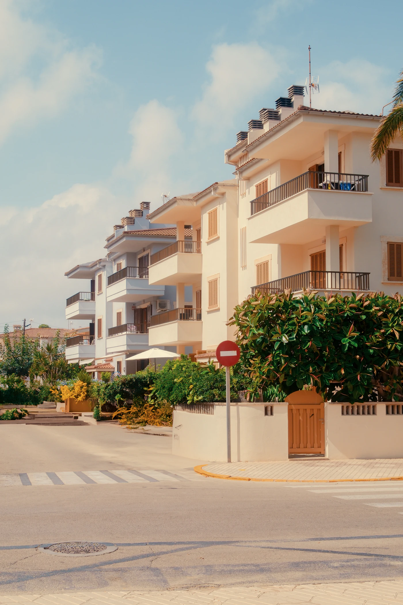 A row of clean white low-rise apartment buildings beside a quiet street