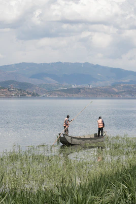 A couple of men standing on top of a boat