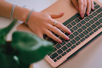 A woman typing on a laptop computer on a desk