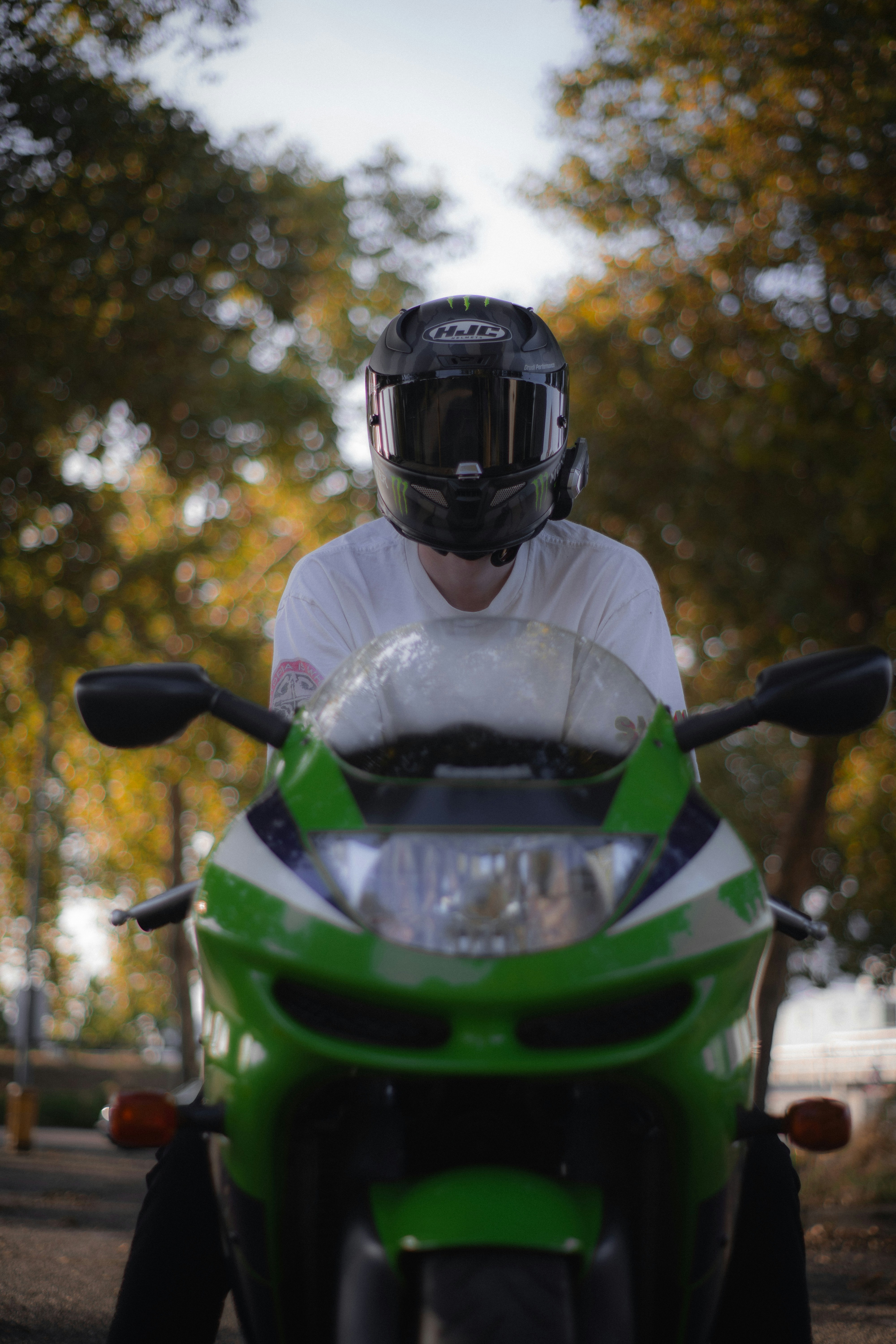 A man wearing a helmet sitting on a green motorcycle