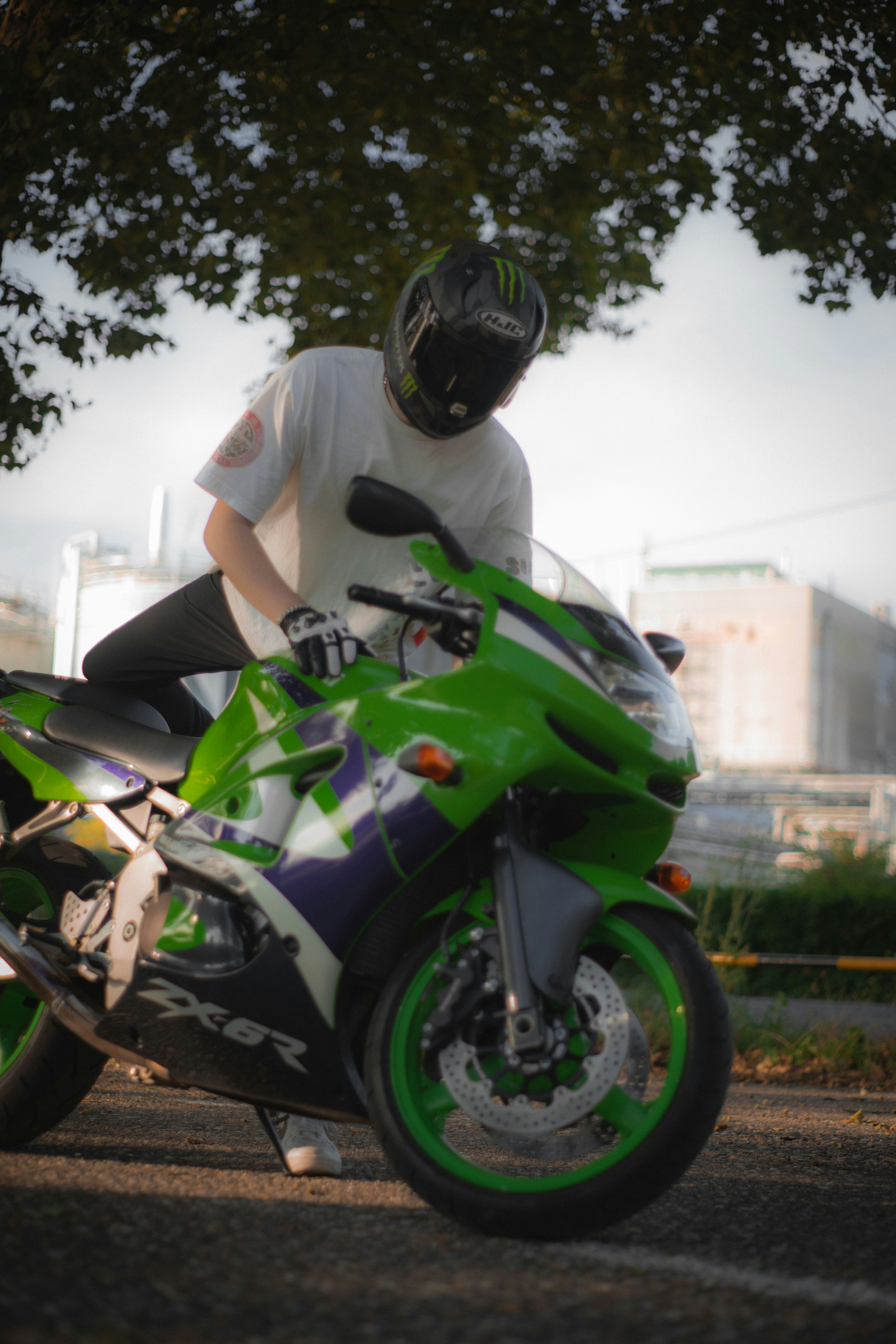 A man riding a green motorcycle down a street