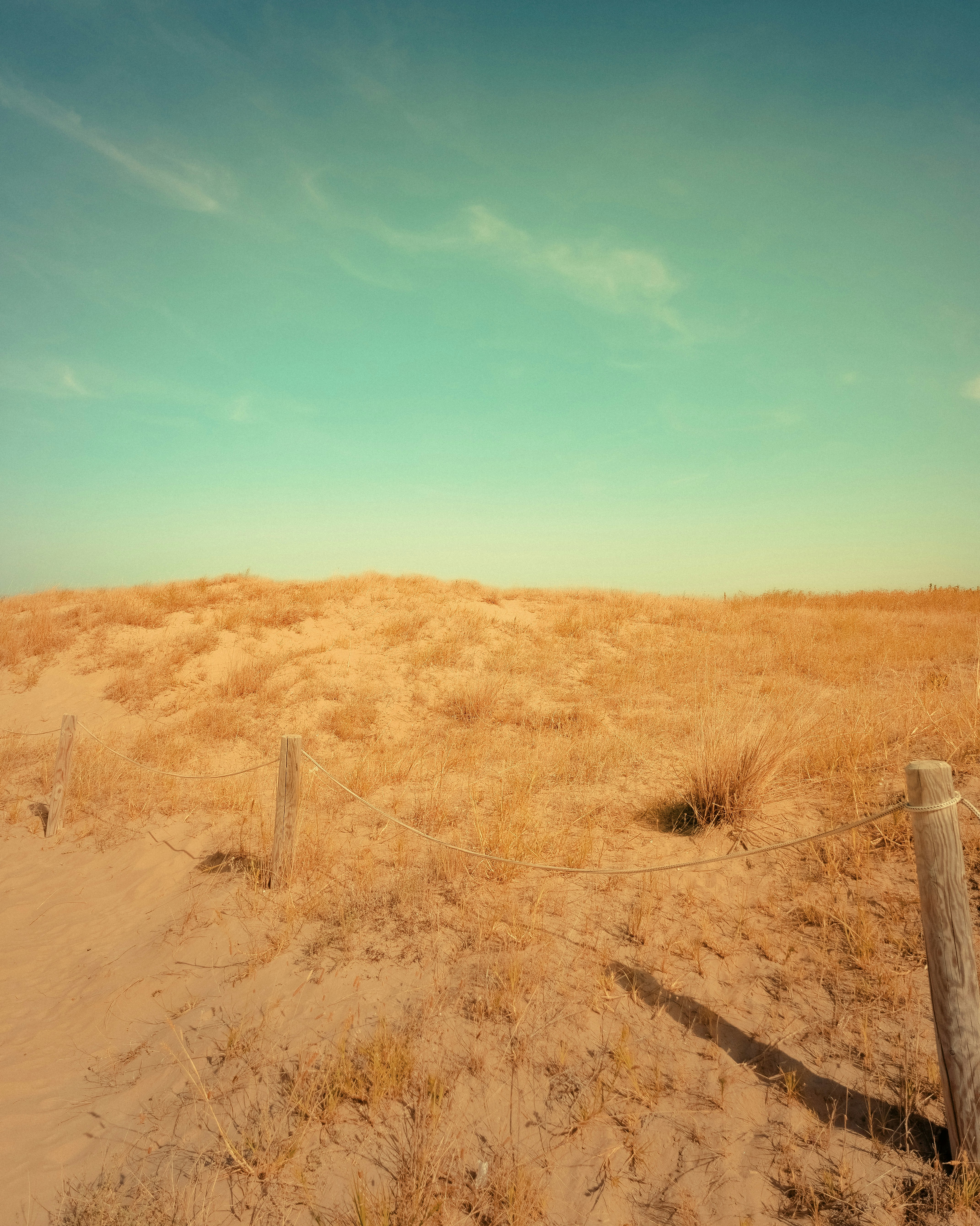 A fence in the middle of a sandy field