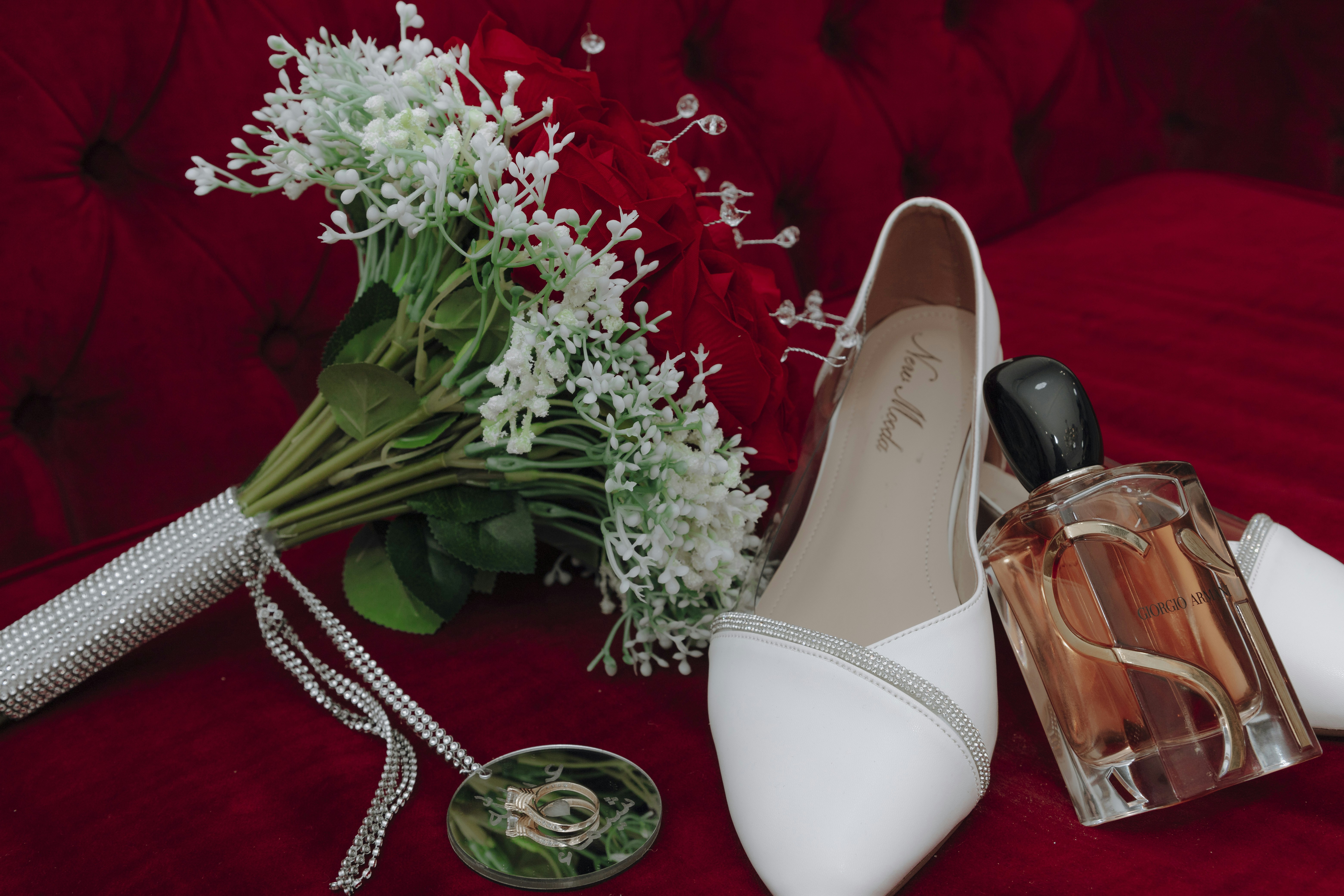 Un ramo de flores y un par de zapatos en un sofá rojo