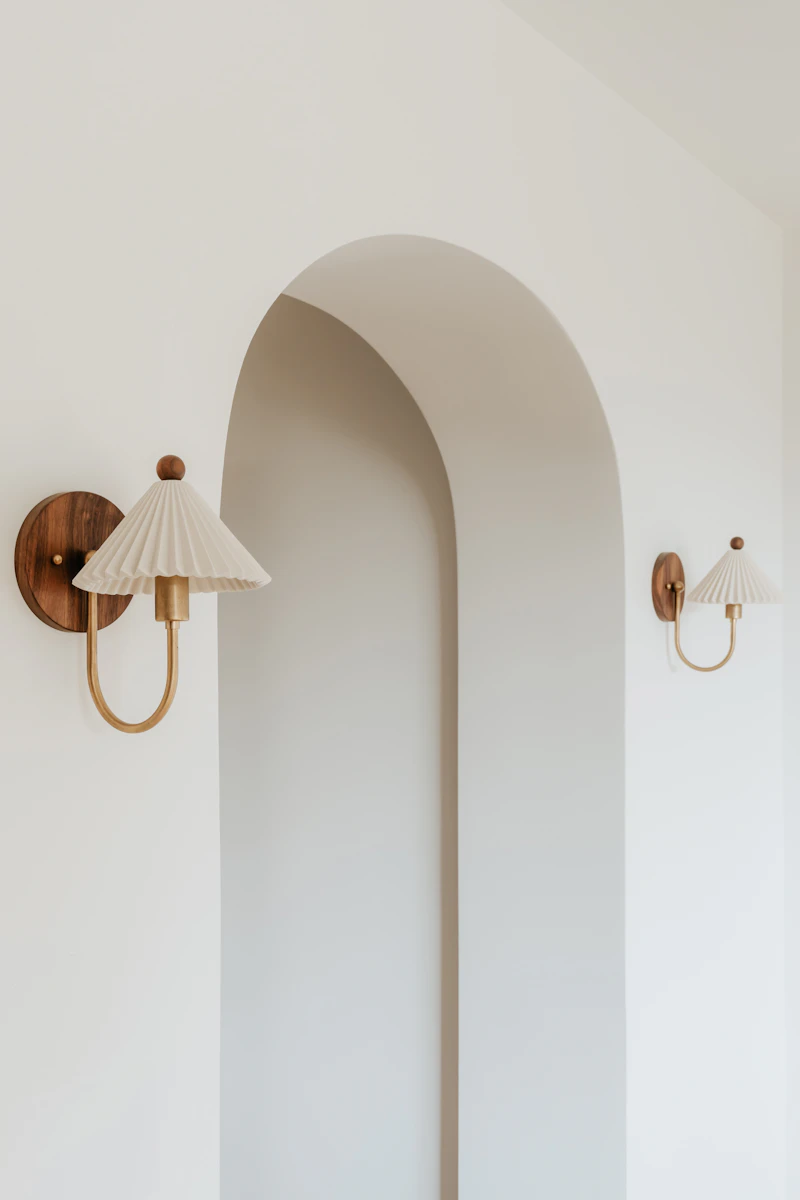 A serene cream room with two wall lamps and warm afternoon light