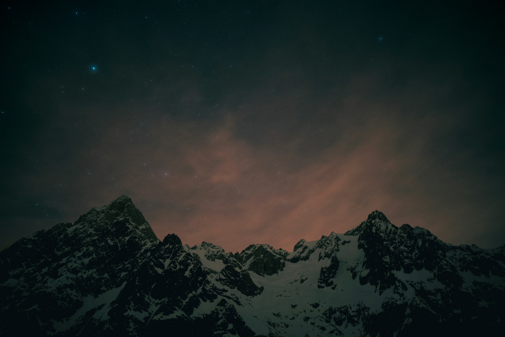 A view of a mountain at night with the moon in the sky