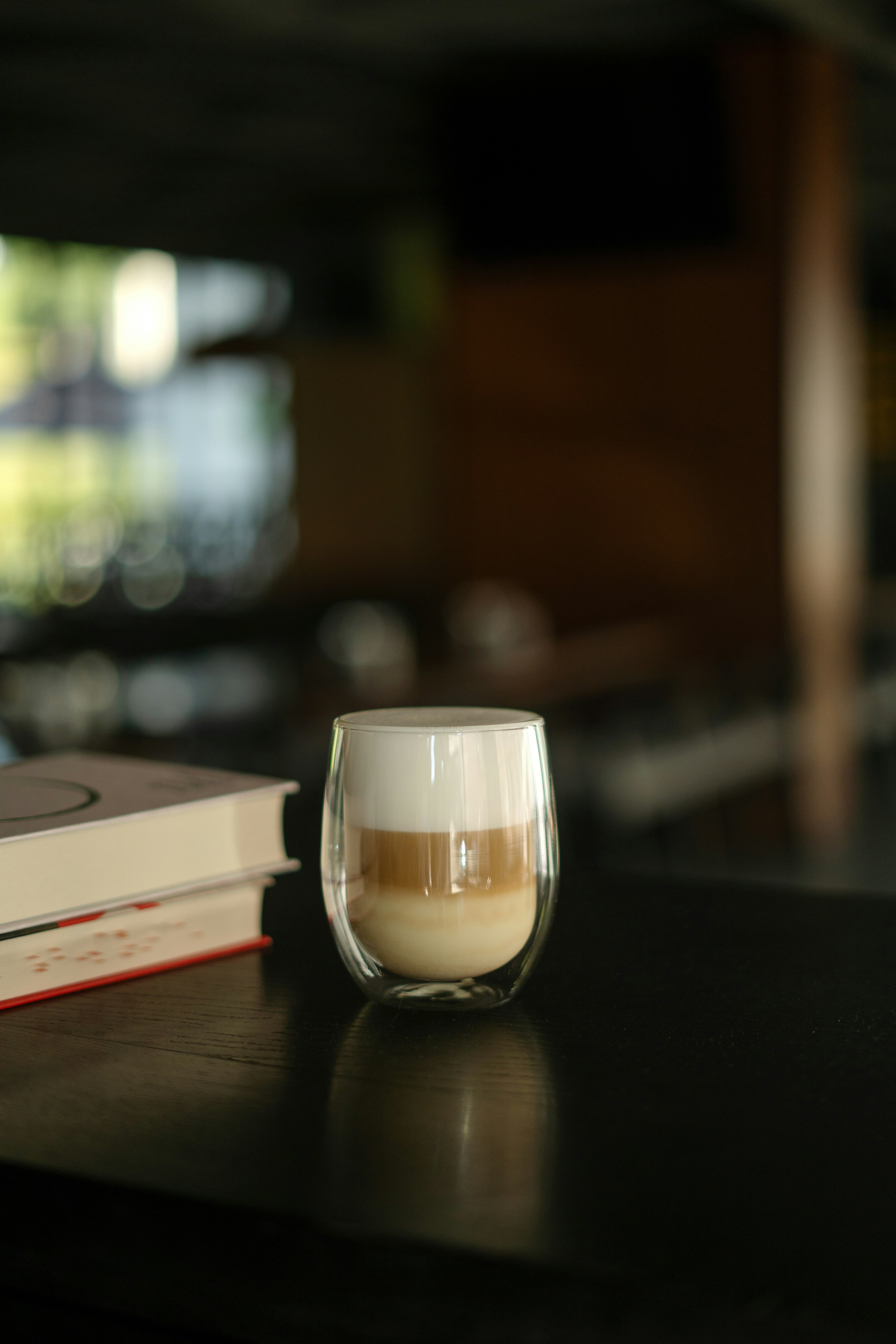 A cup of coffee sitting on top of a table next to a book