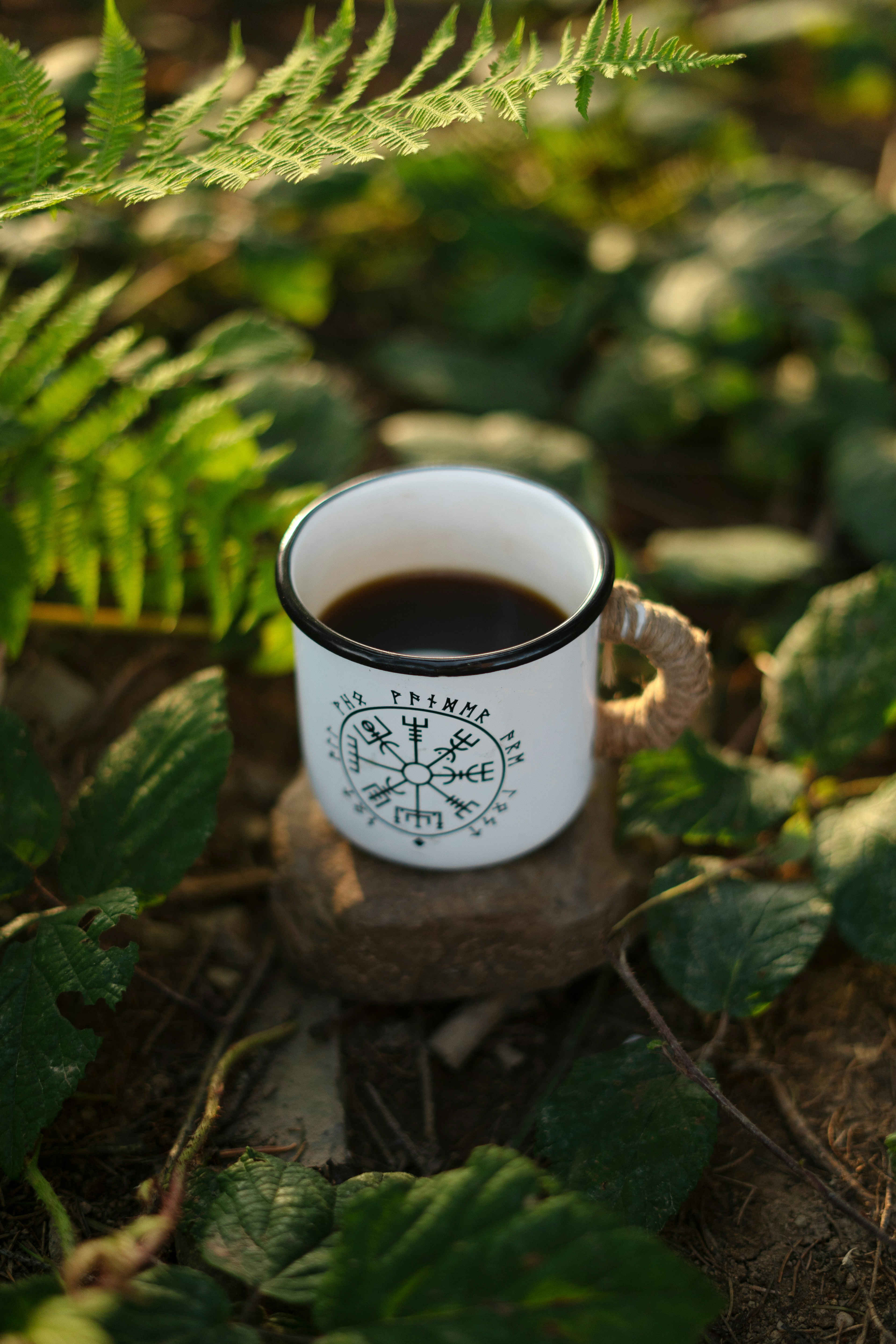 A cup of coffee sitting on top of a forest floor
