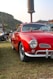 A red car parked in a field next to other cars