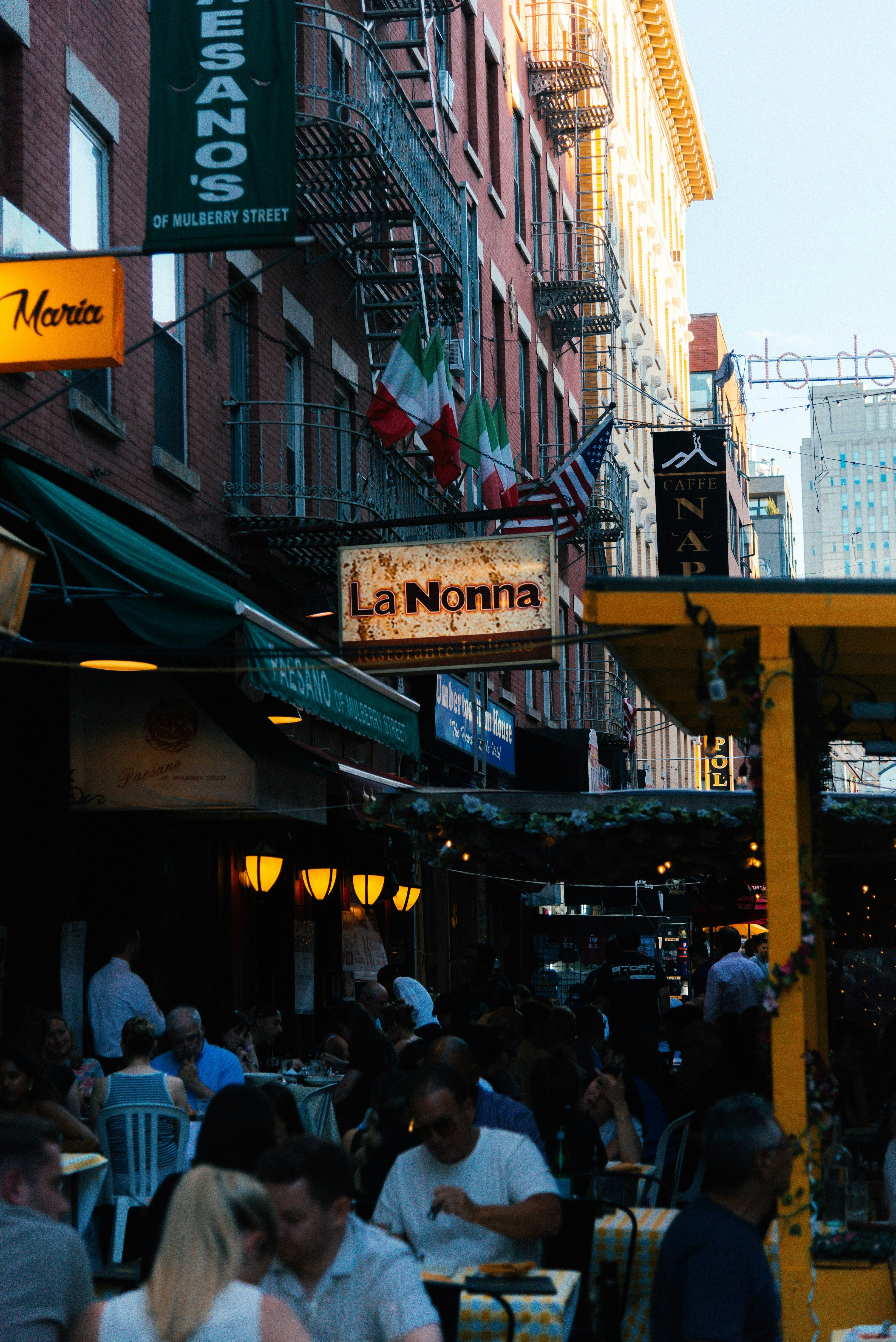 A group of people walking down a street next to tall buildings