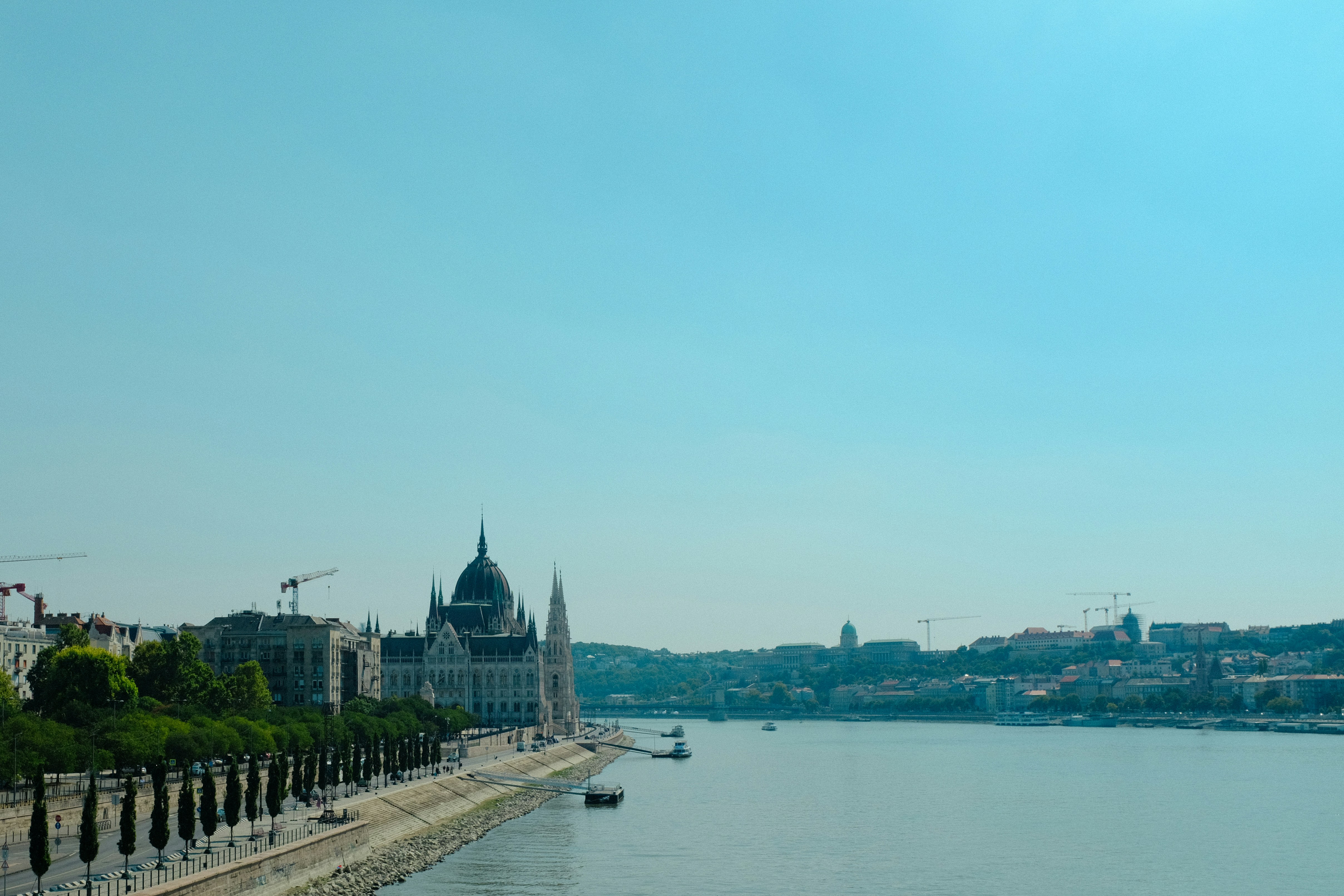 Budapest cityscape with Parliament building, bright daytime, blue Danube river, clear sky, warm European light