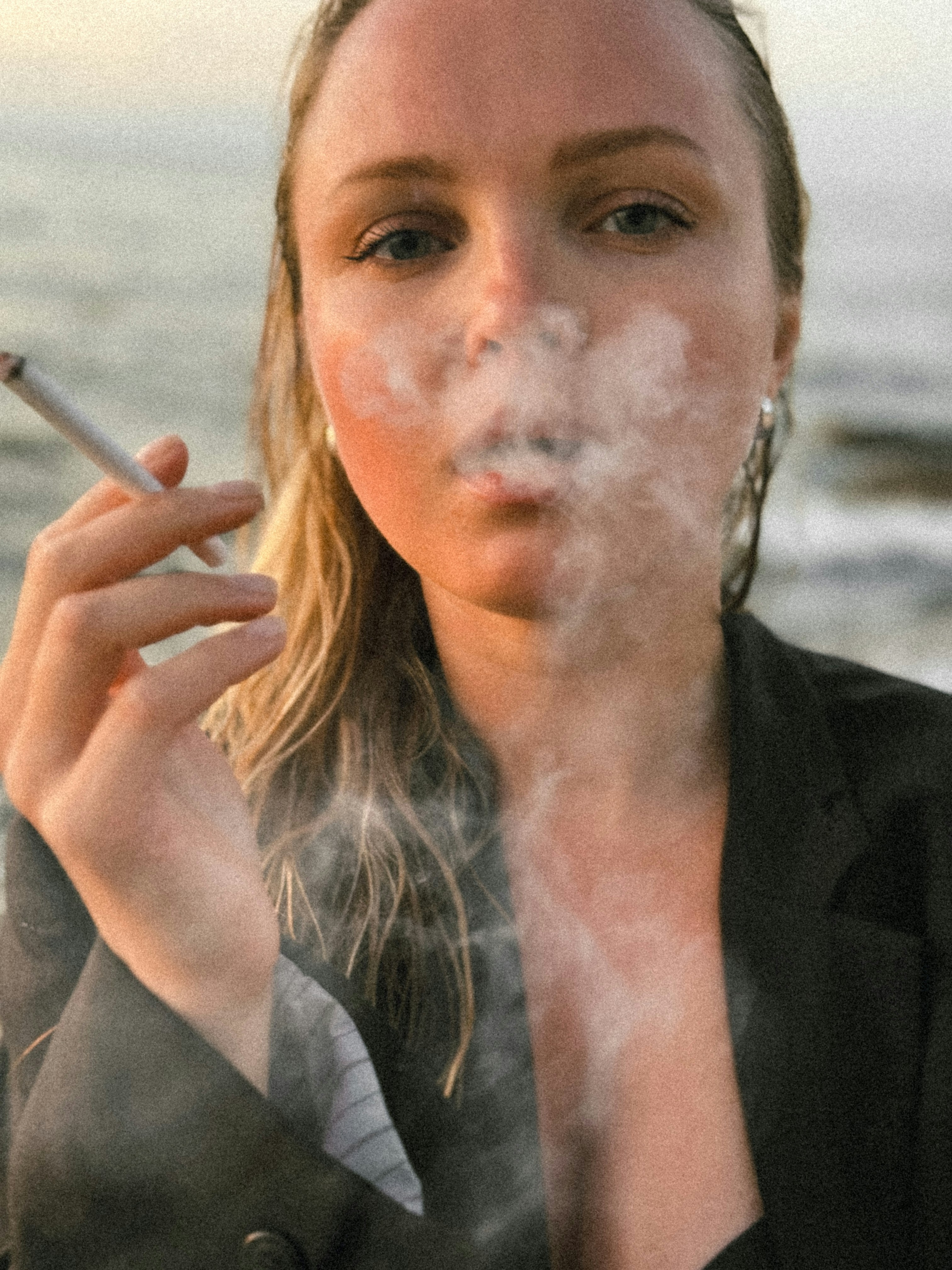 A woman smoking a cigarette on the beach