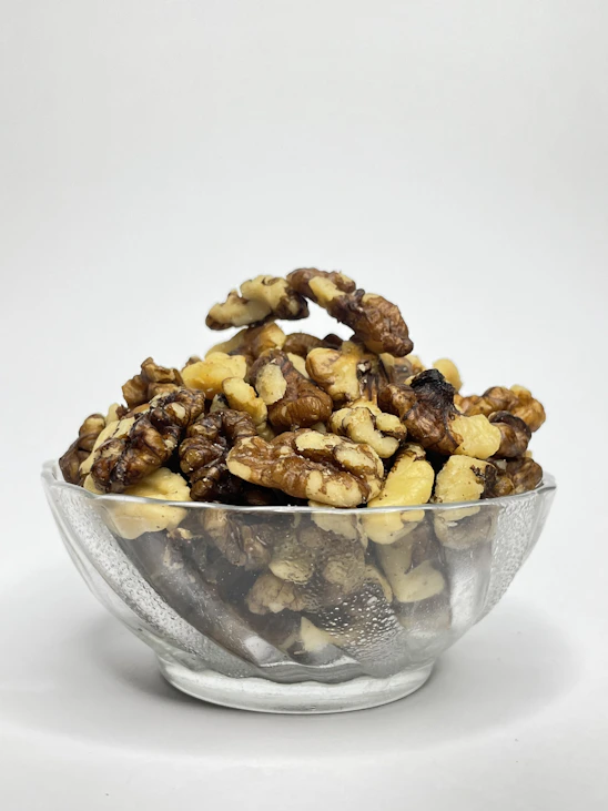 A glass bowl filled with nuts on top of a white table