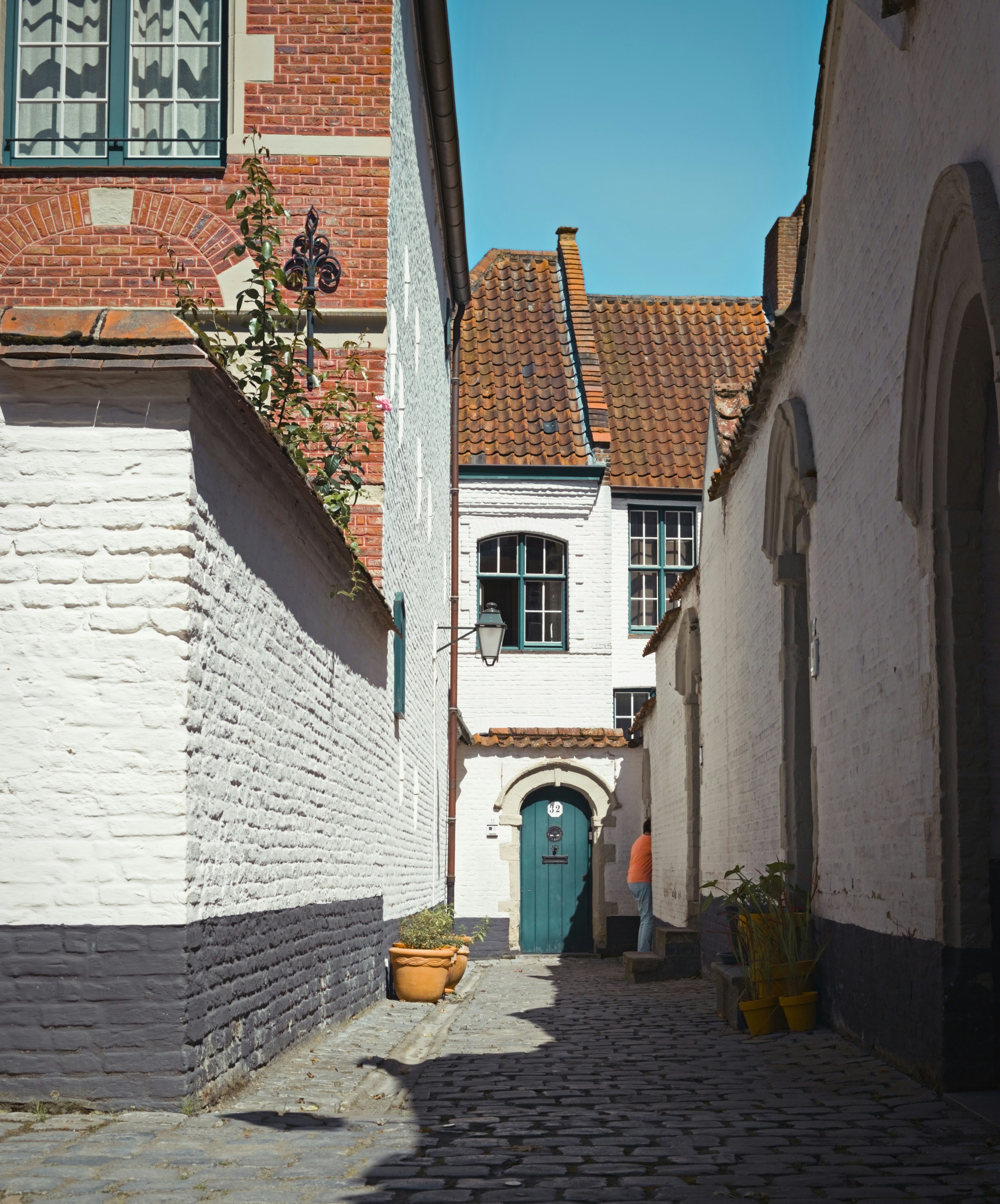 A cobblestone street lined with white brick buildings