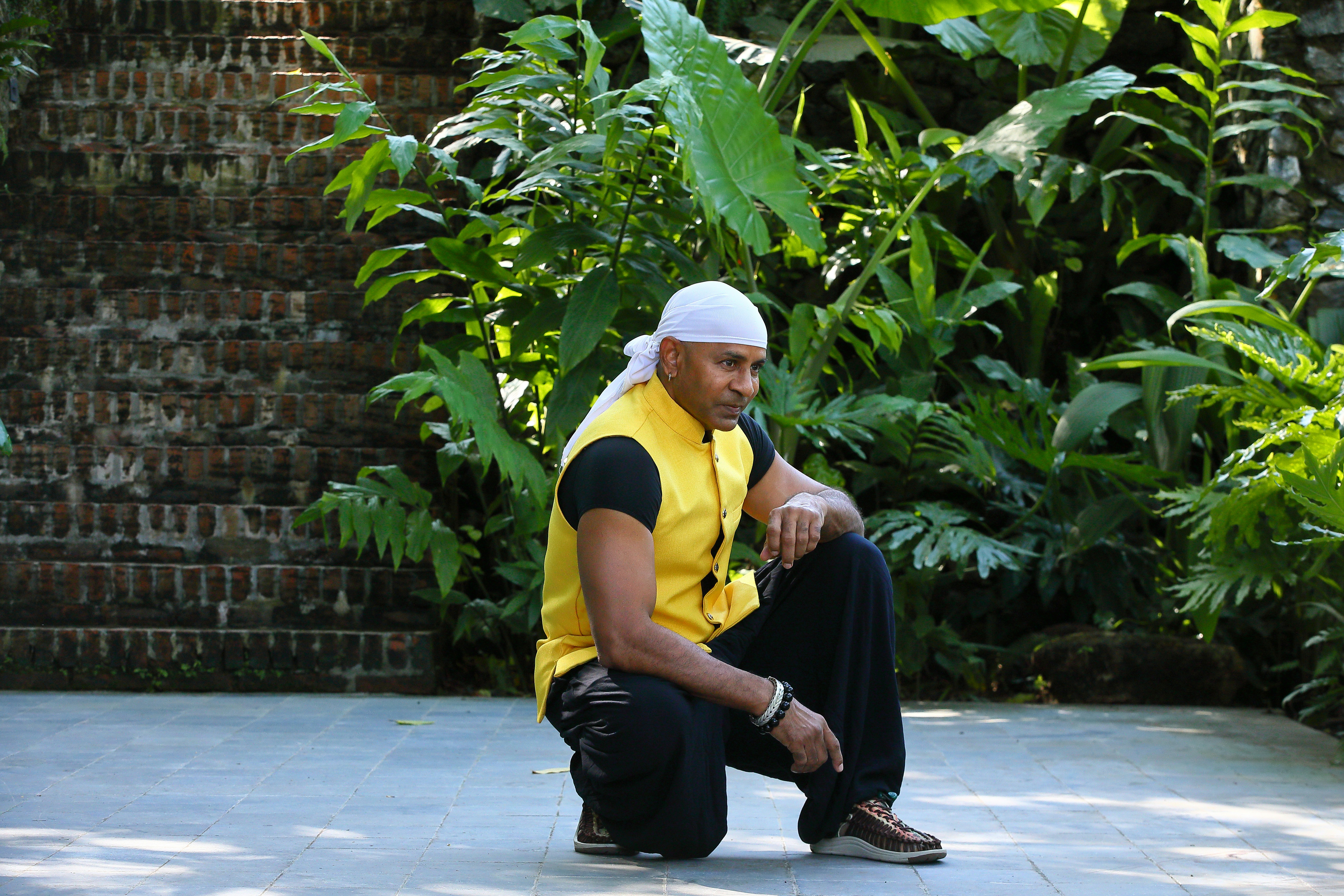 A man sitting on the ground in front of some plants