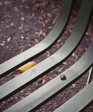 A close up of a metal bench with a leaf on it