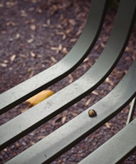 A close up of a metal bench with a leaf on it